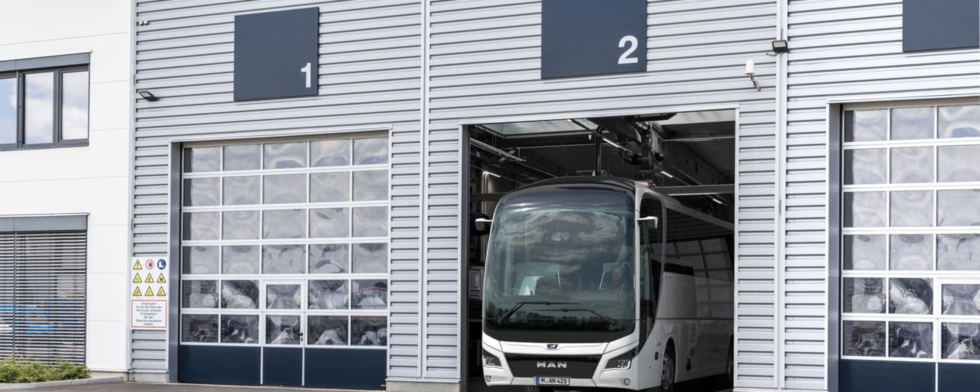 Ein Bus steht in einer nummerierten Garage eines modernen Betriebsgebäudes.