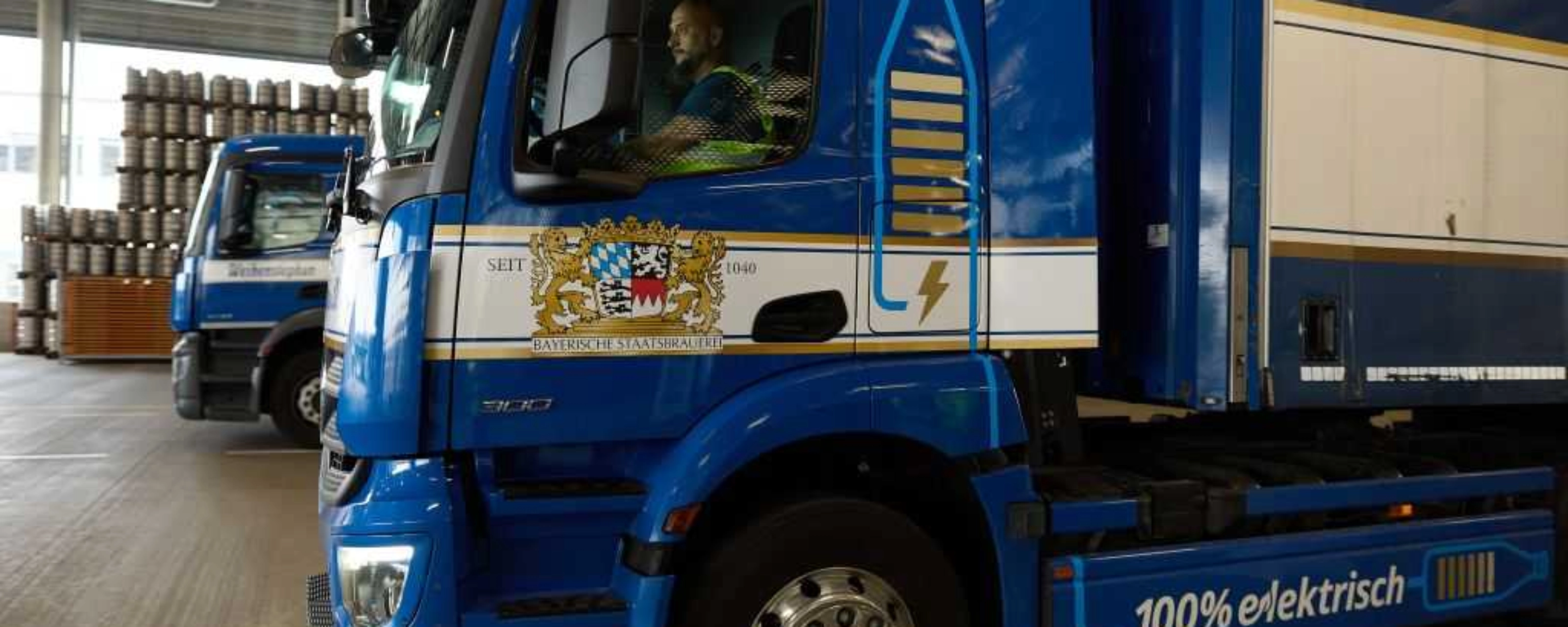 Lastwagen steht in einer Logistikhalle, Fahrer sitzt im Führerhaus.
