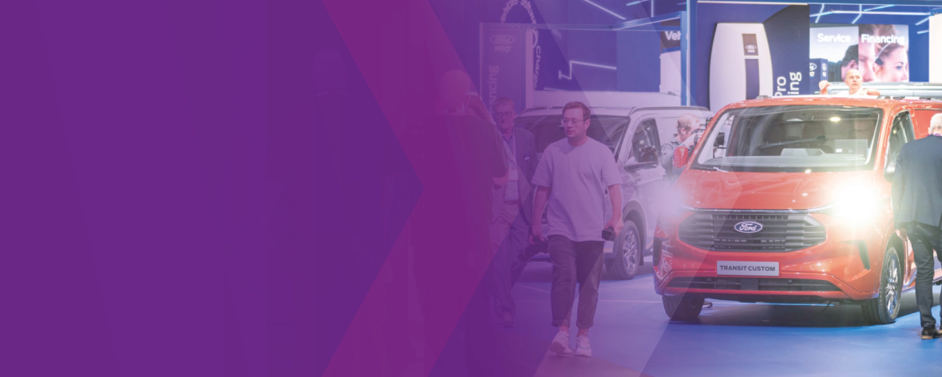 Visitors walking past a Ford Transit Custom at an IAA trade fair booth.