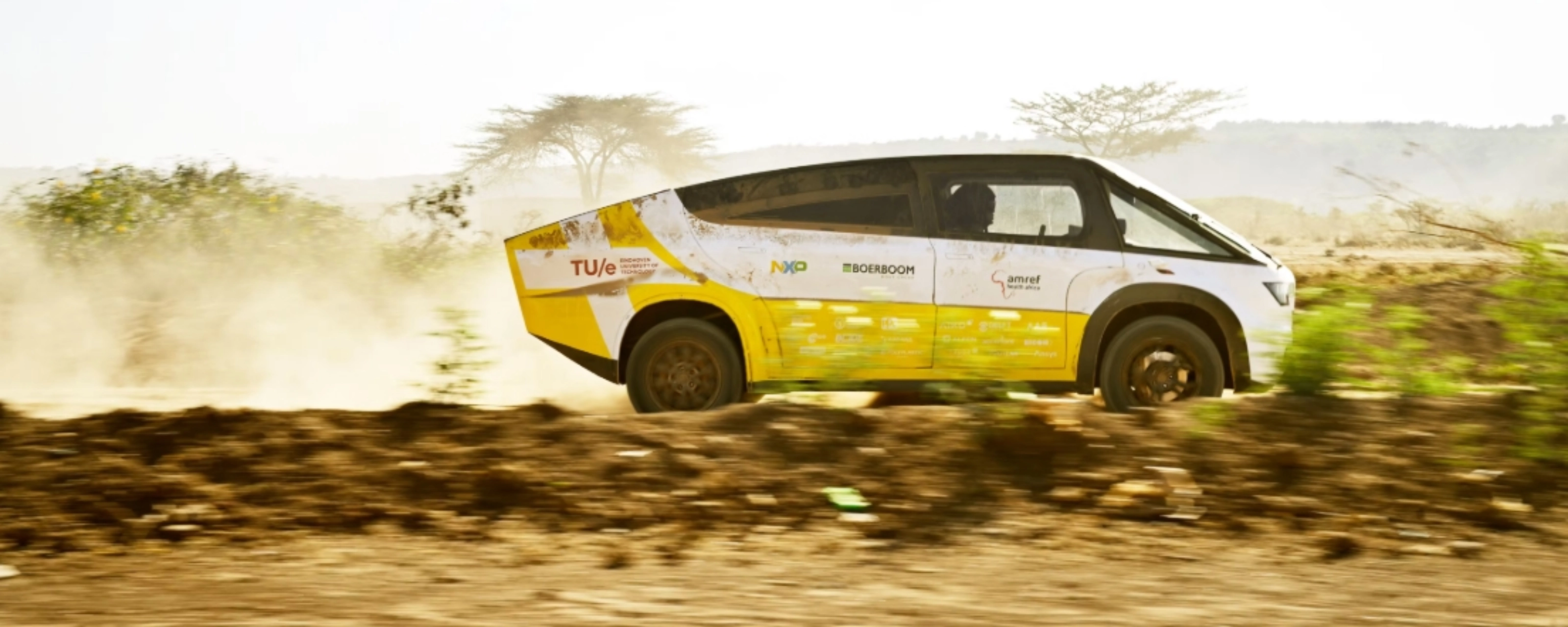 Fahrzeug des Solar Team Eindhoven fährt auf einer staubigen unbefestigten Straße.