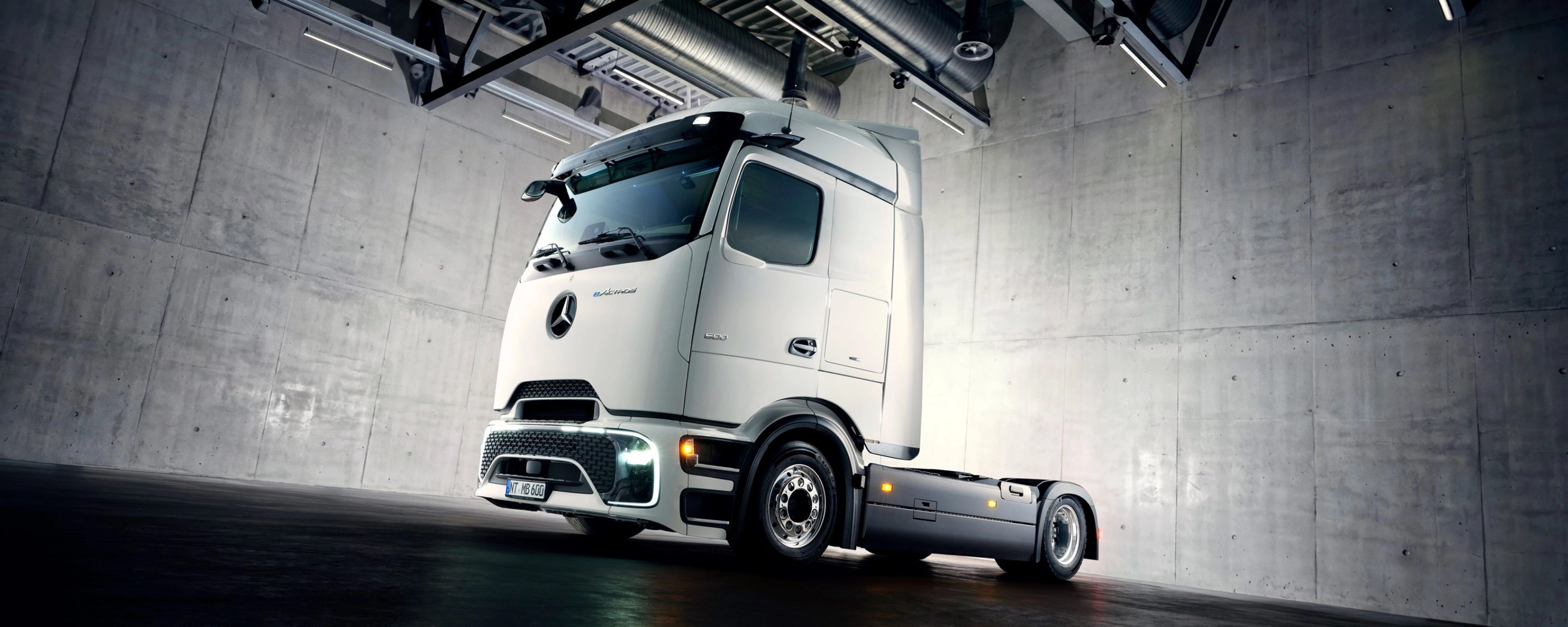 Autonomes Lkw-Fahrgestell in Industriehalle unter Scheinwerfern.