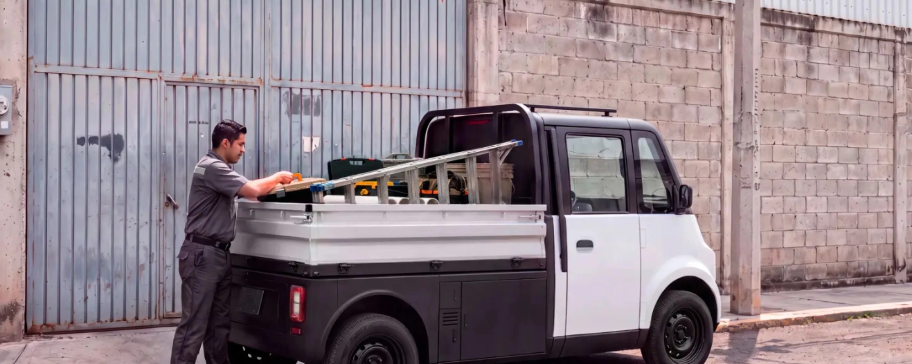 Compact Olinia utility vehicle being loaded at the roadside.