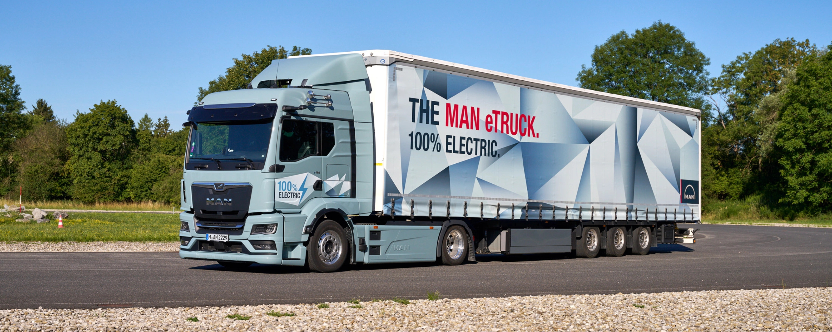 MAN truck with a trailer featuring a large graphic parked on a paved area.