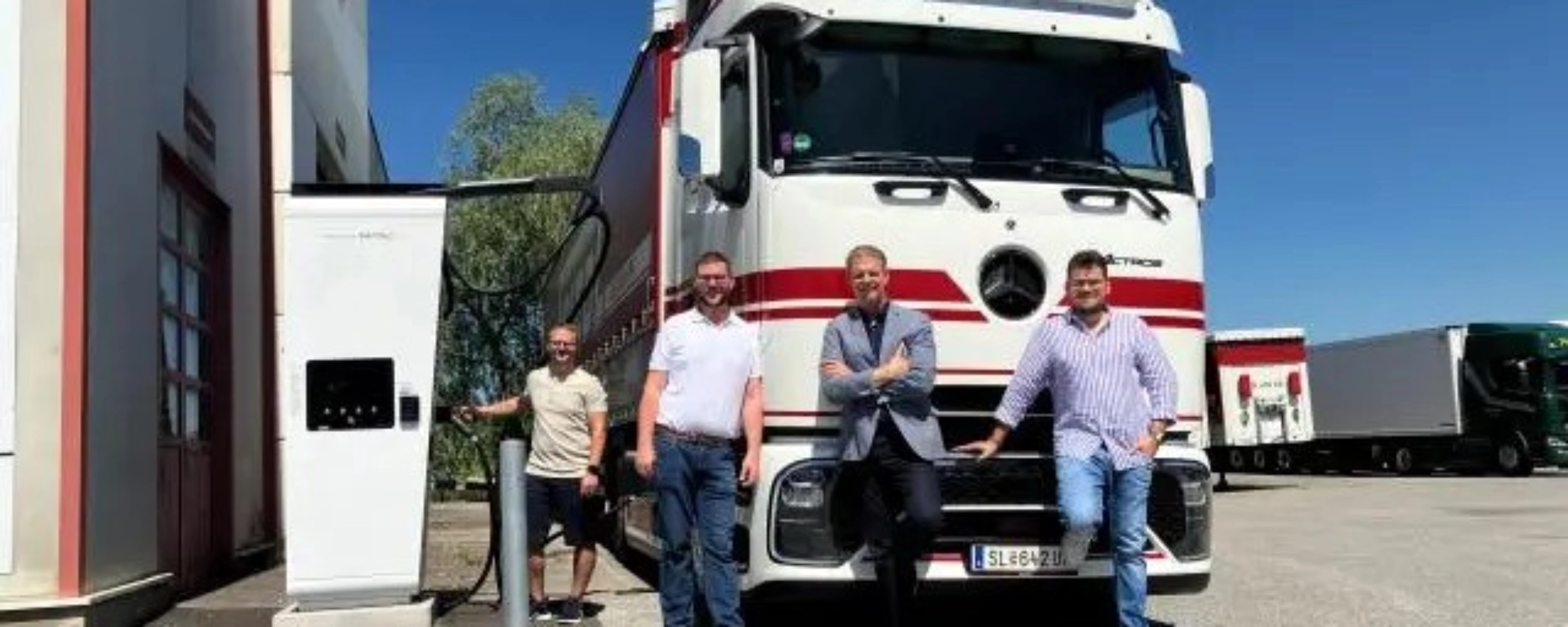 Vier Männer stehen vor einem weißen Frigel Lkw.