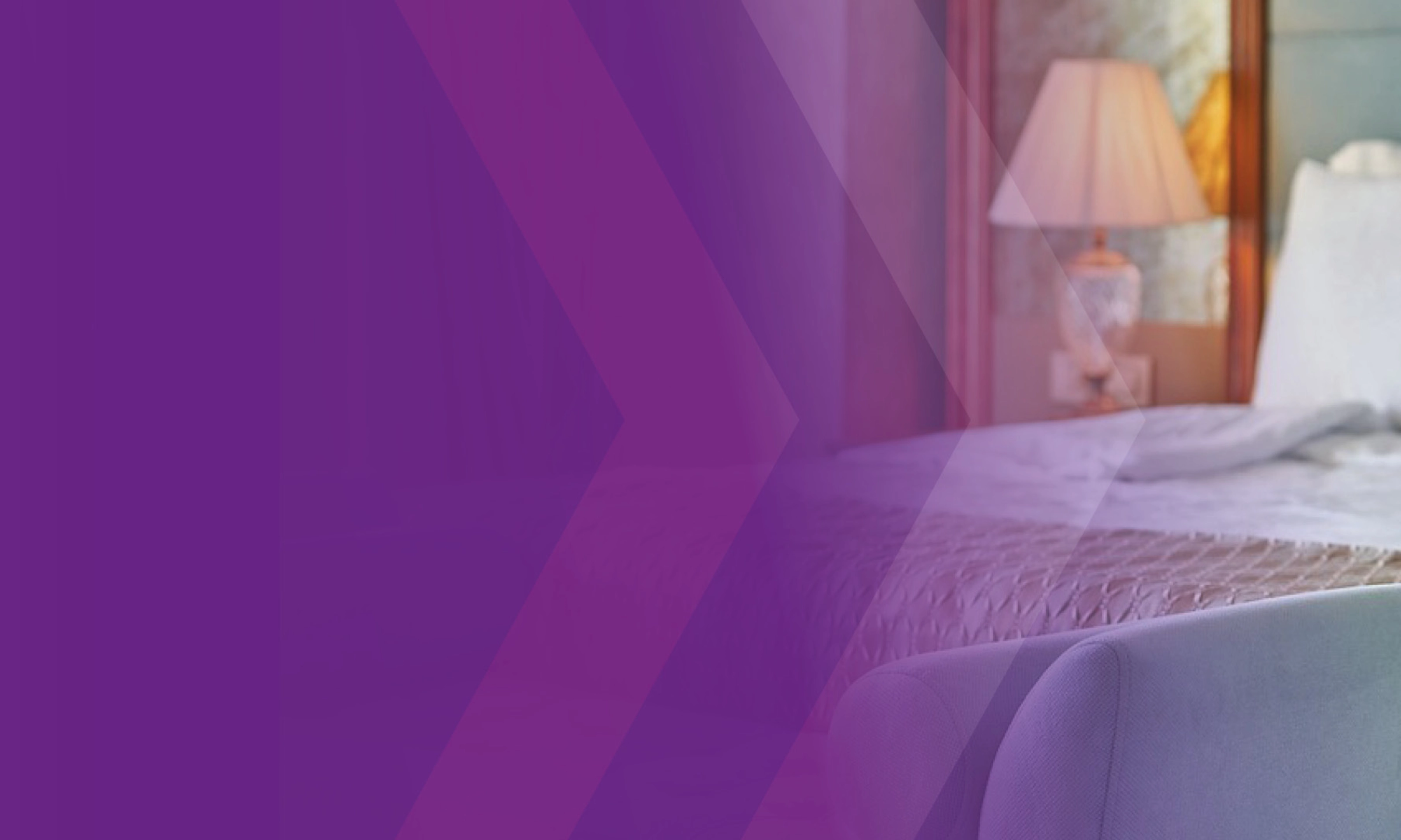 Hotelzimmer mit ordentlich gemachtem Bett und Nachttischlampe.