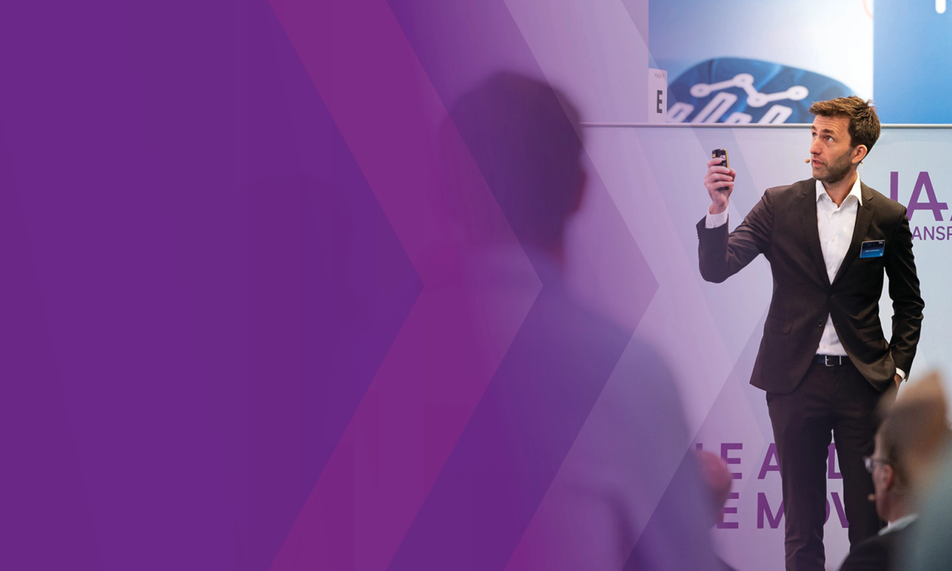 Man giving a presentation and holding a remote at a conference.