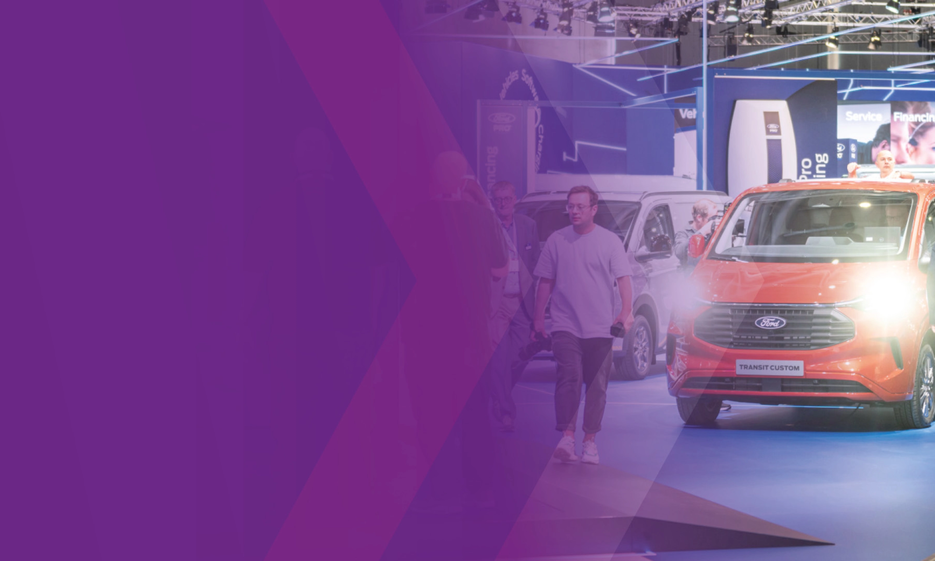 Visitors walking past a Ford Transit Custom at an IAA trade fair booth.