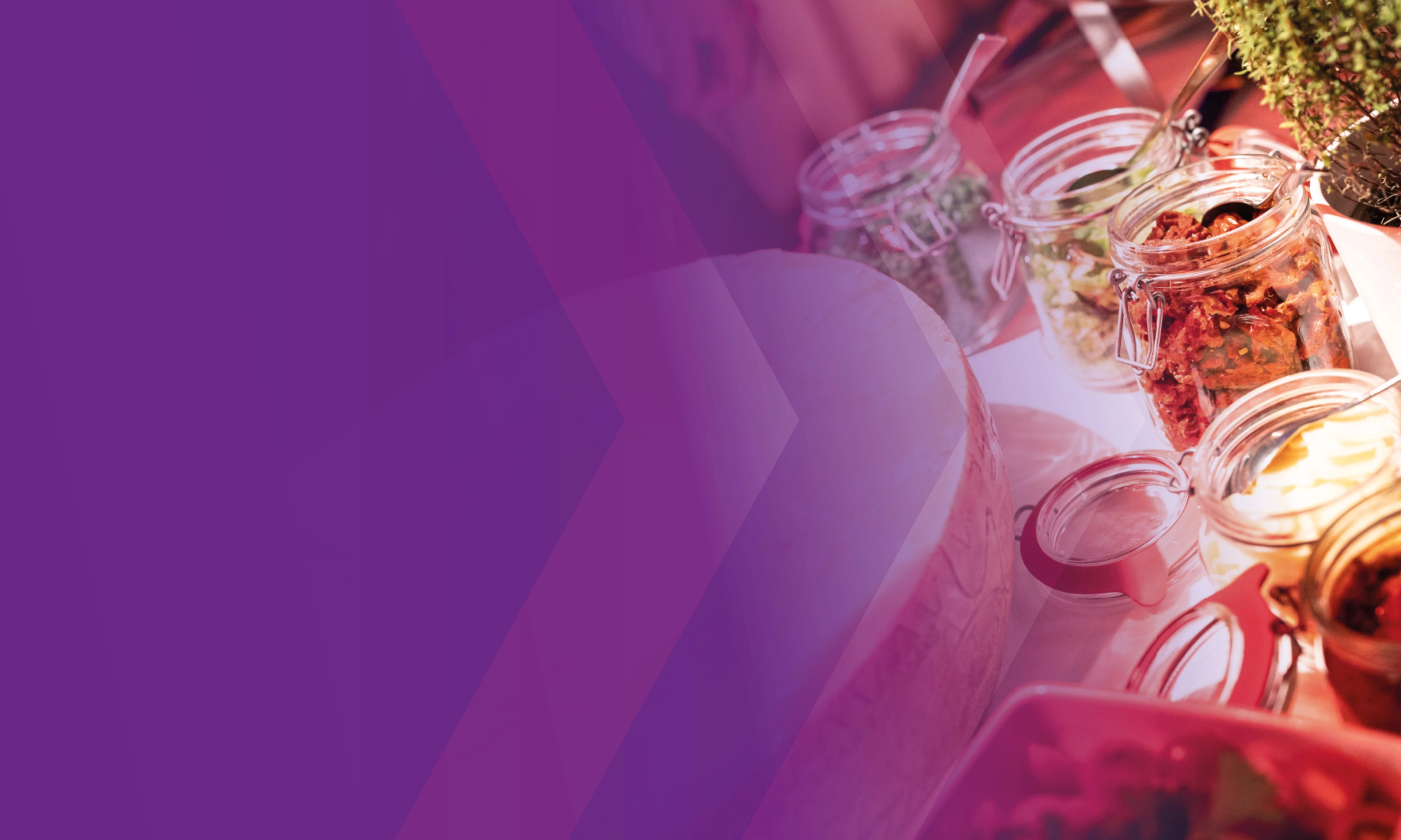 Catering-Tisch mit Gläsern voller Antipasti und frischen Kräutern.