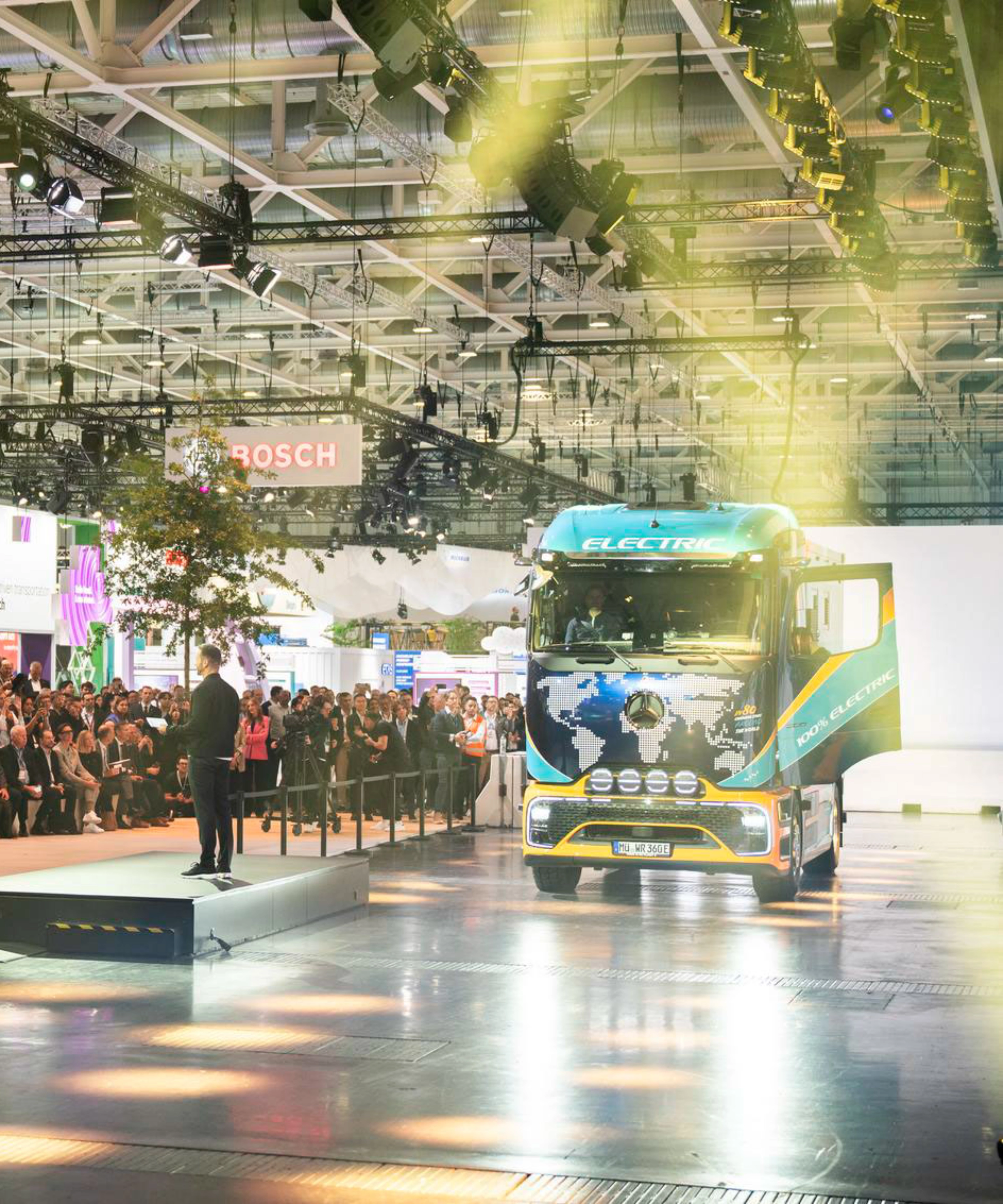 Lkw fährt in einer Messehalle an einem großen Publikum vorbei.