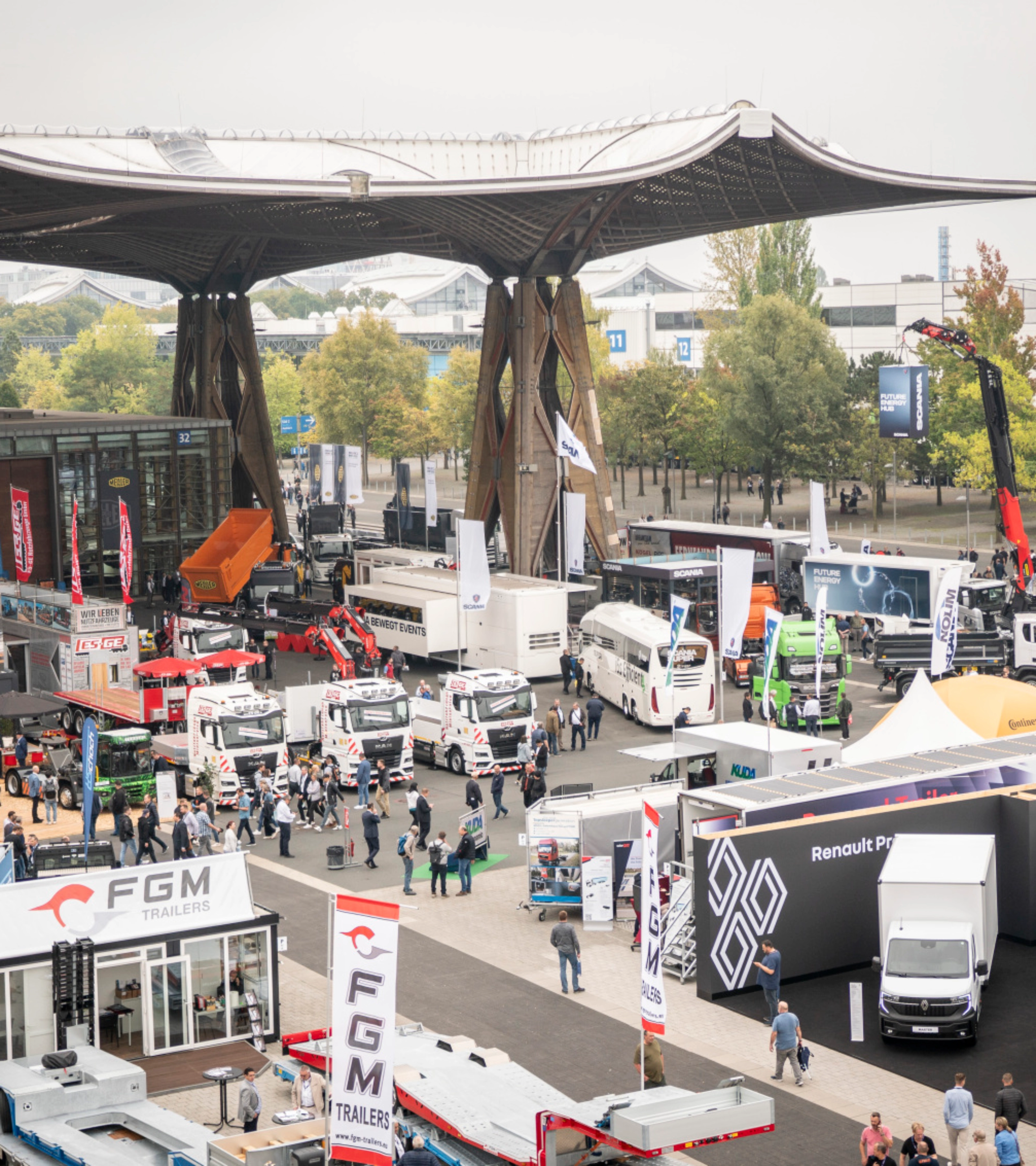 Man presenting vehicle technology on a lit-up stage at a trade fair with audience watching.