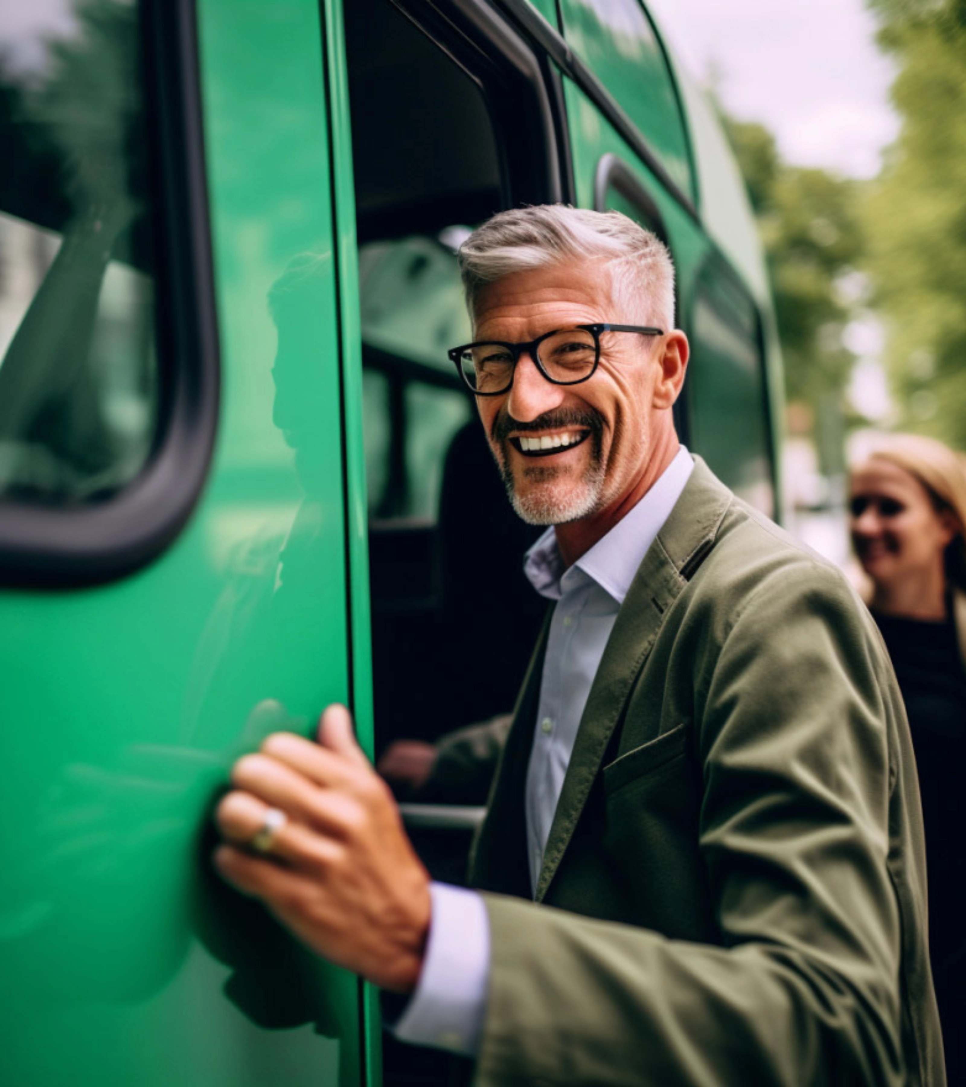 Smiling man with glasses boarding a green bus outdoors.