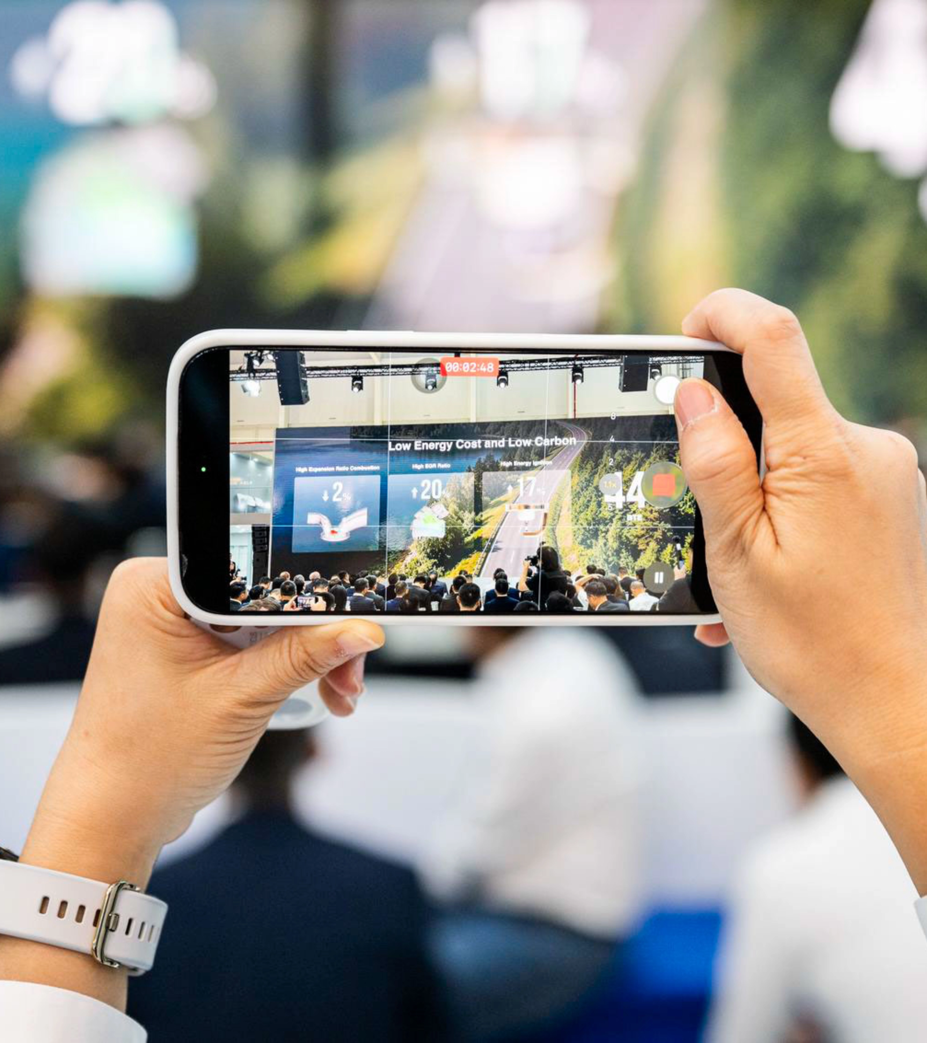 Person taking a photo of an event with a smartphone.