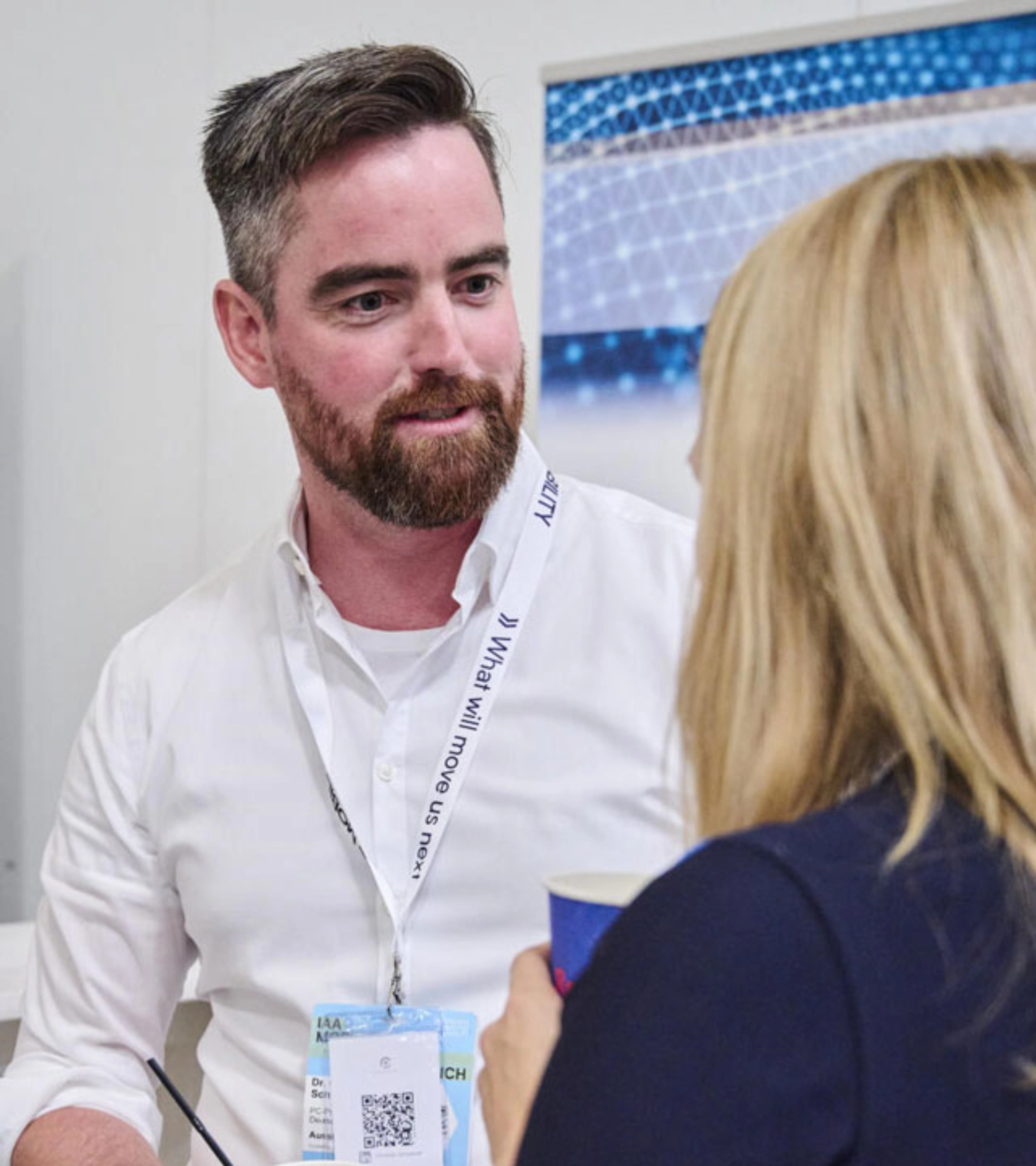 Two people talking in front of exhibition booths with banners and name tags