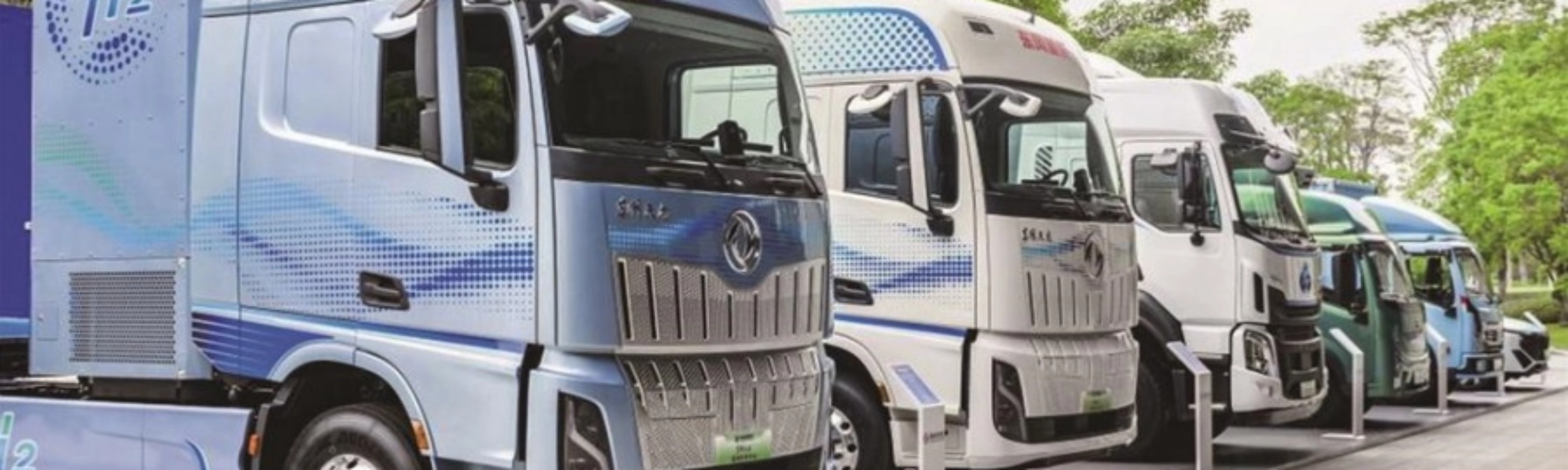 Reihe von Wasserstoff-Lkw mit H2-Beschriftung im Außenbereich.