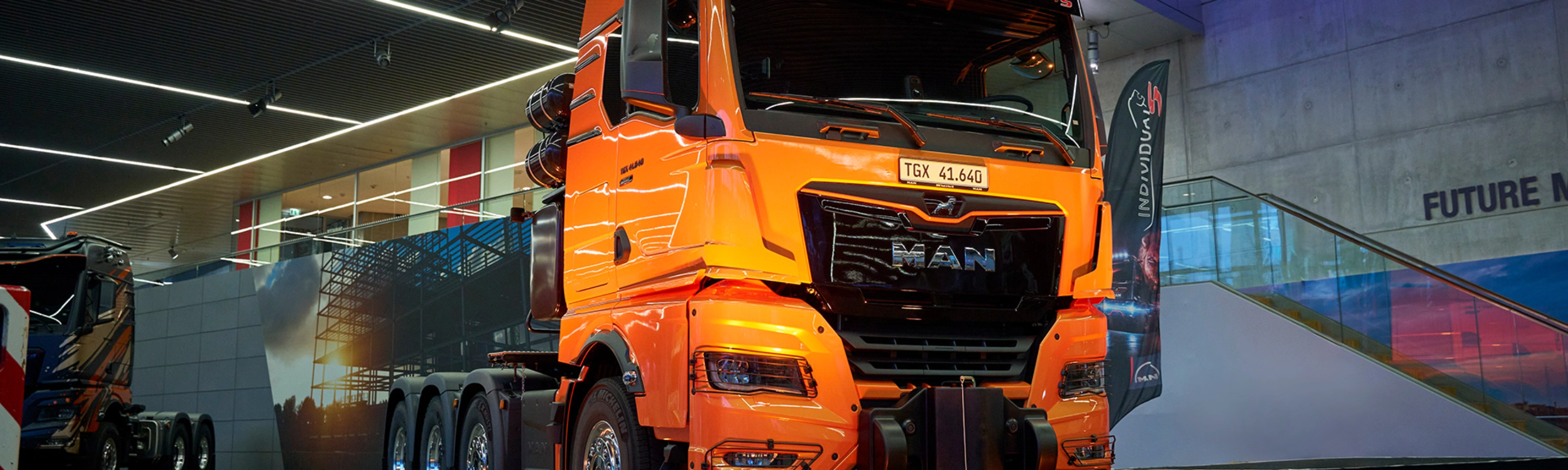 Orange MAN TGX 41.640 truck displayed at an indoor exhibition.