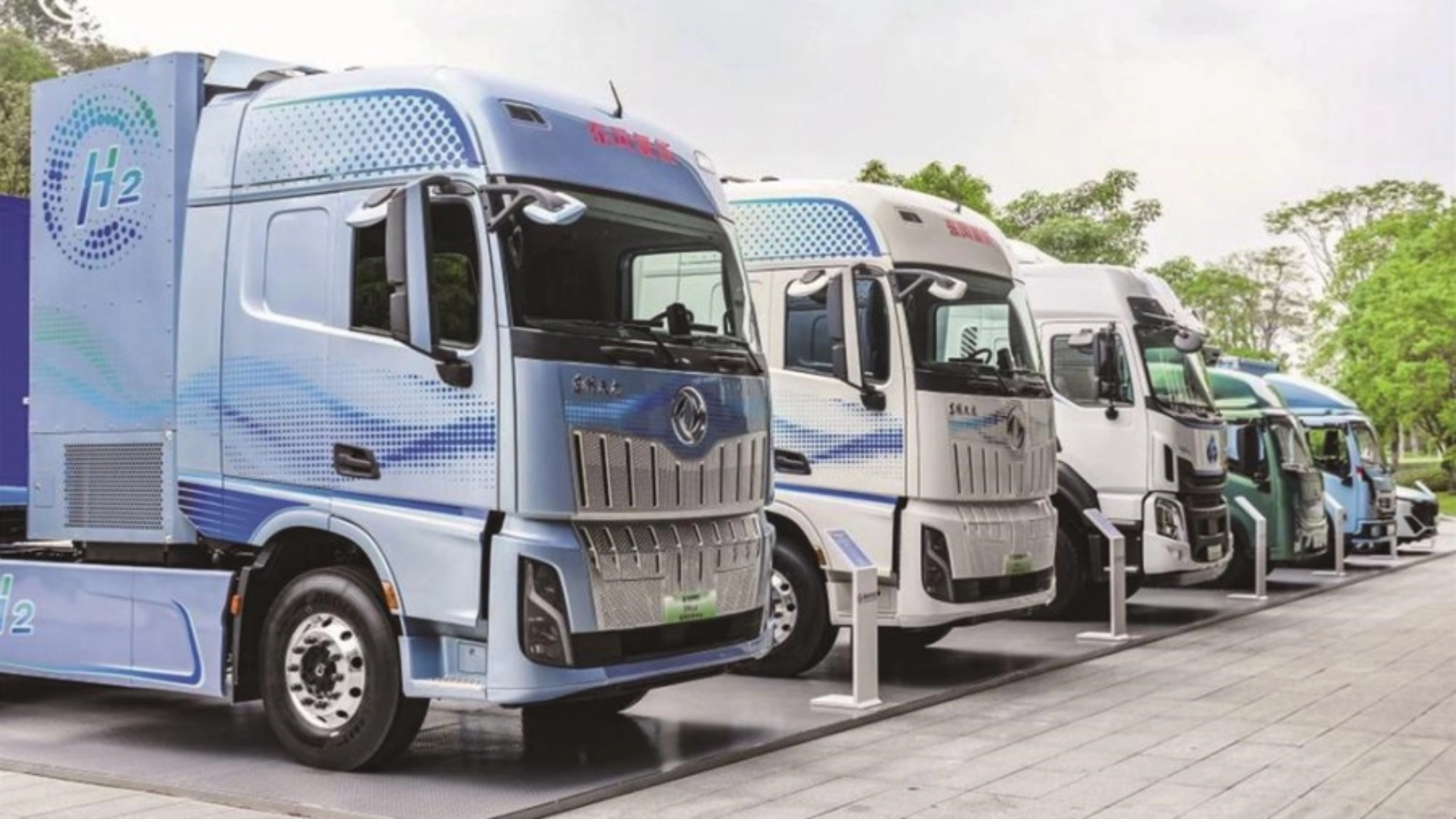 Reihe von Wasserstoff-Lkw mit H2-Beschriftung im Außenbereich.