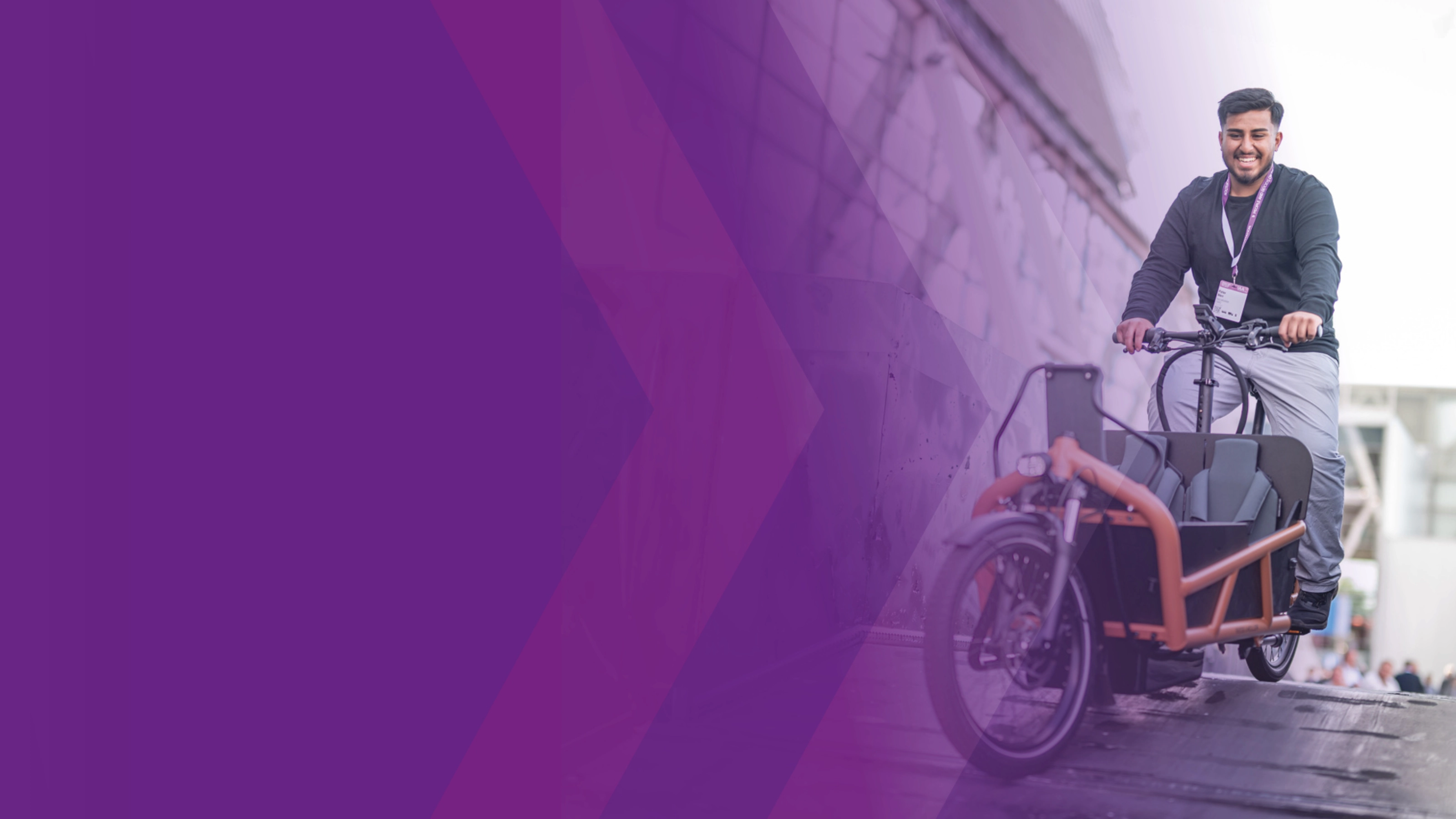 Man riding a cargo bike down a ramp at an outdoor event.
