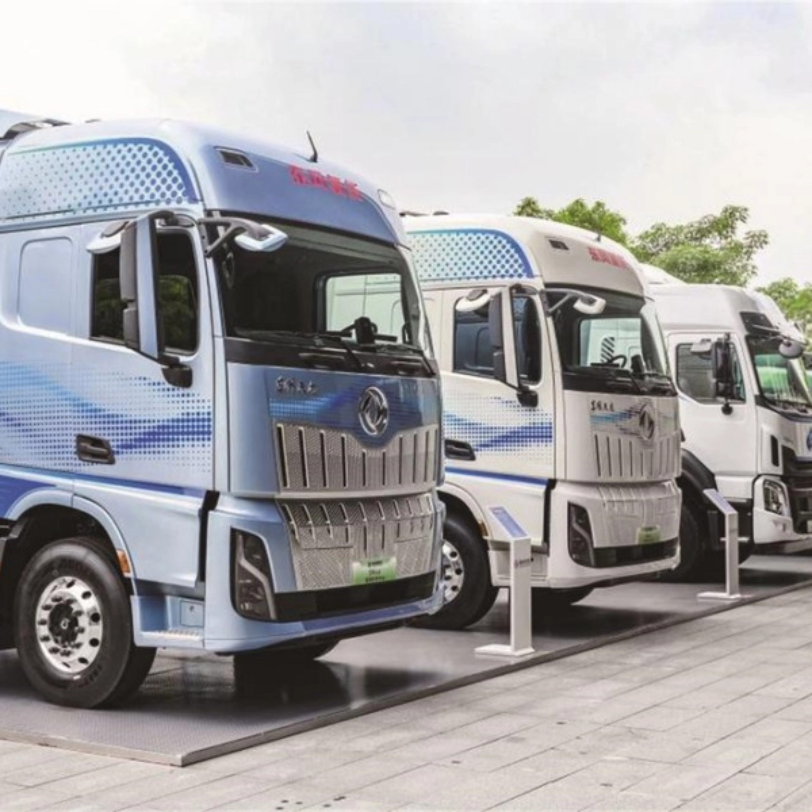Reihe von Wasserstoff-Lkw mit H2-Beschriftung im Außenbereich.