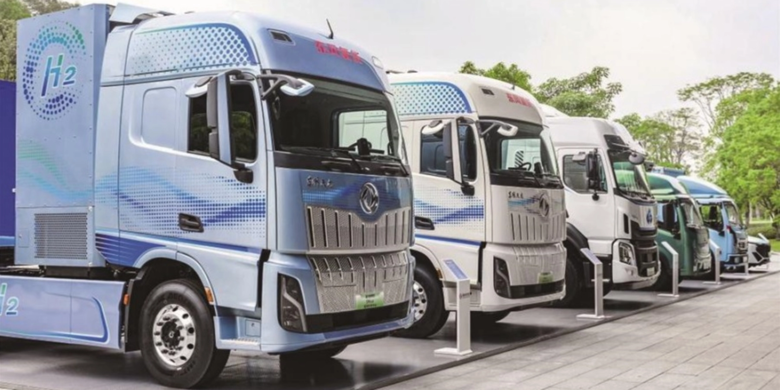Reihe von Wasserstoff-Lkw mit H2-Beschriftung im Außenbereich.