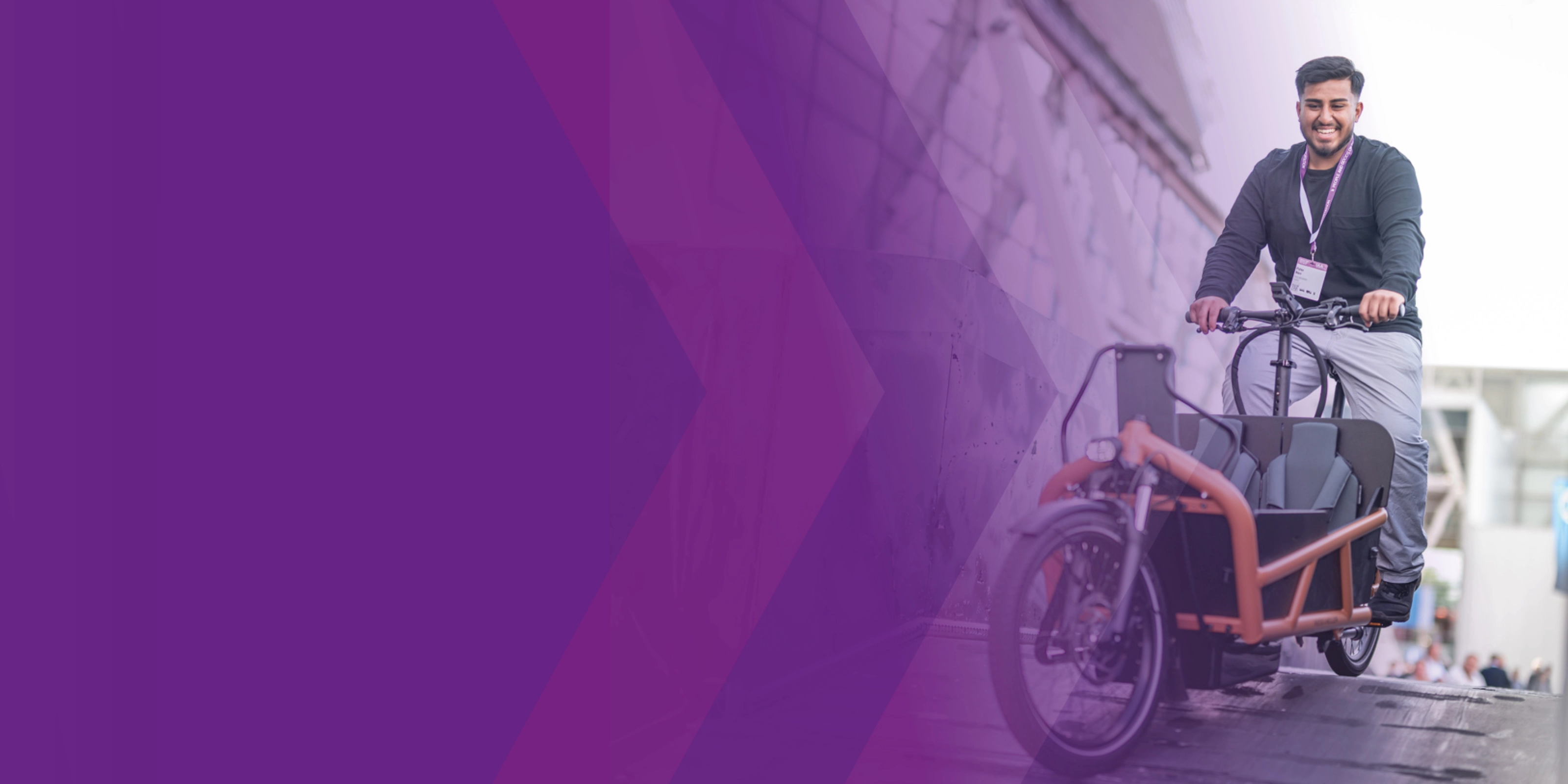 Man riding a cargo bike down a ramp at an outdoor event.