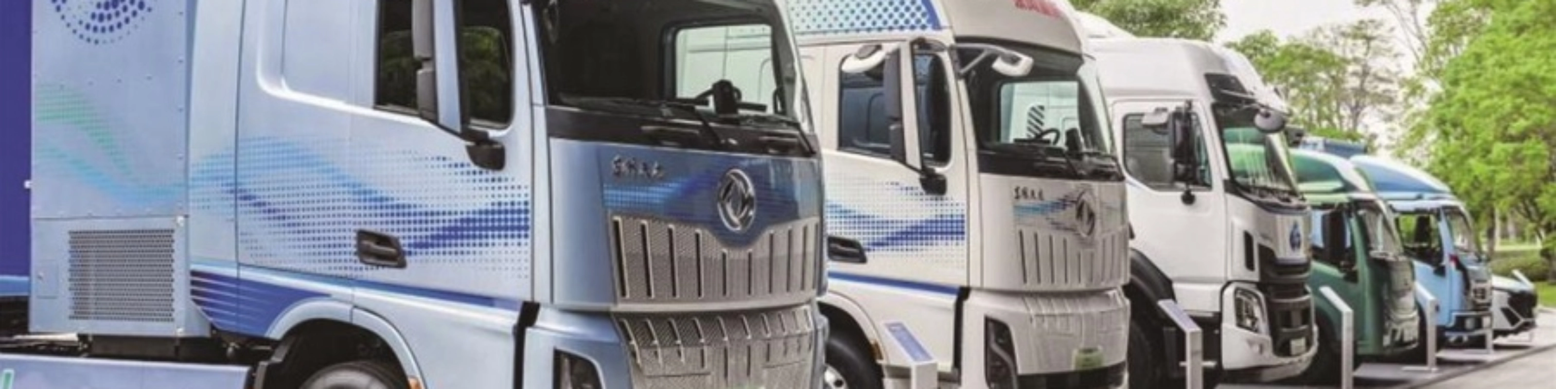 Reihe von Wasserstoff-Lkw mit H2-Beschriftung im Außenbereich.