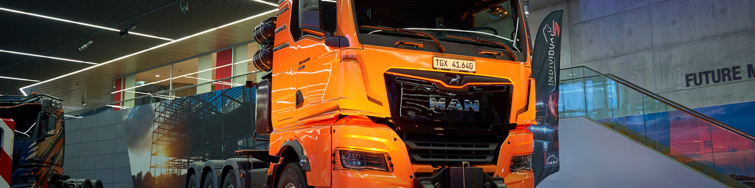Orange MAN TGX 41.640 truck displayed at an indoor exhibition.