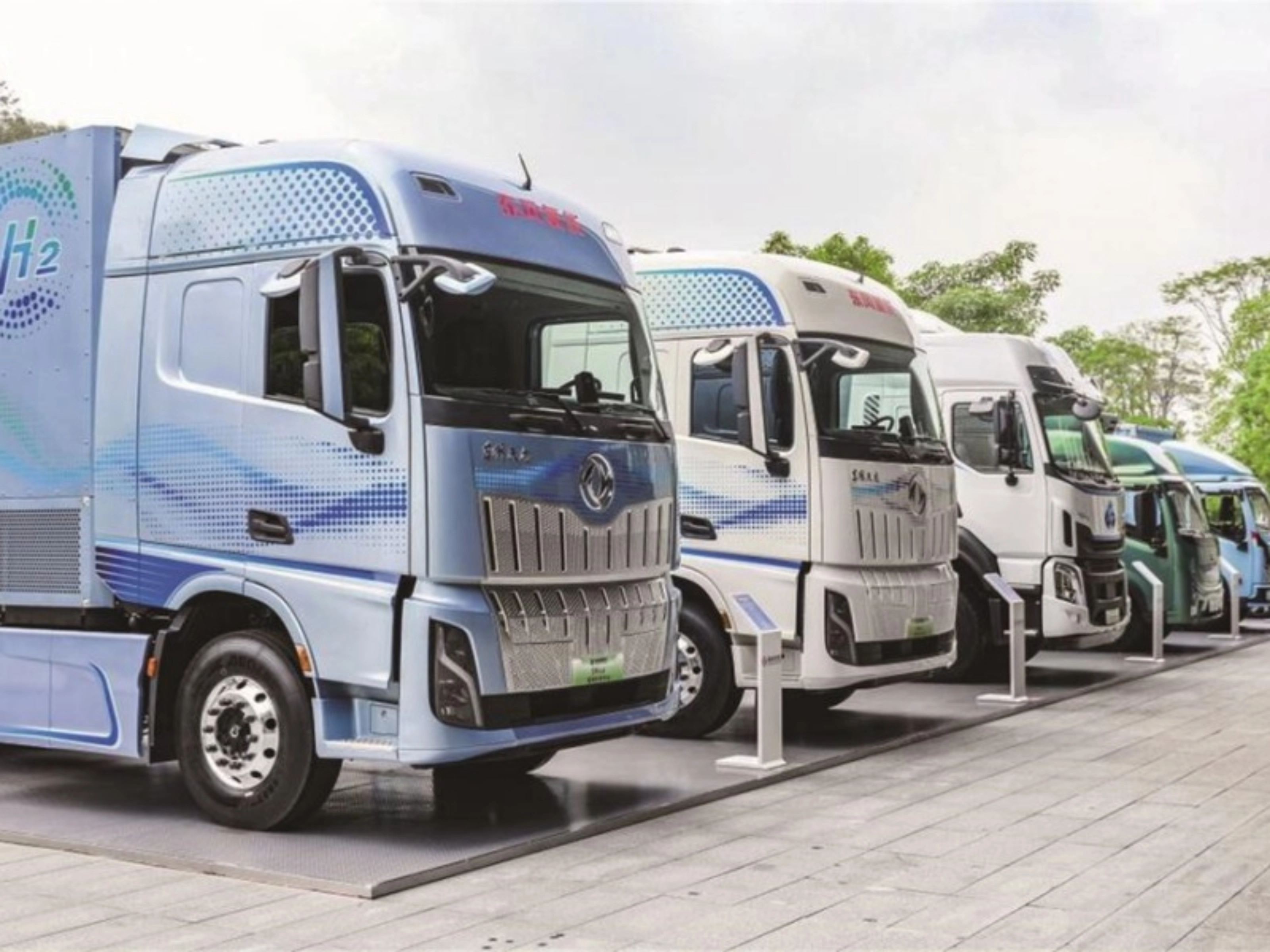 Reihe von Wasserstoff-Lkw mit H2-Beschriftung im Außenbereich.