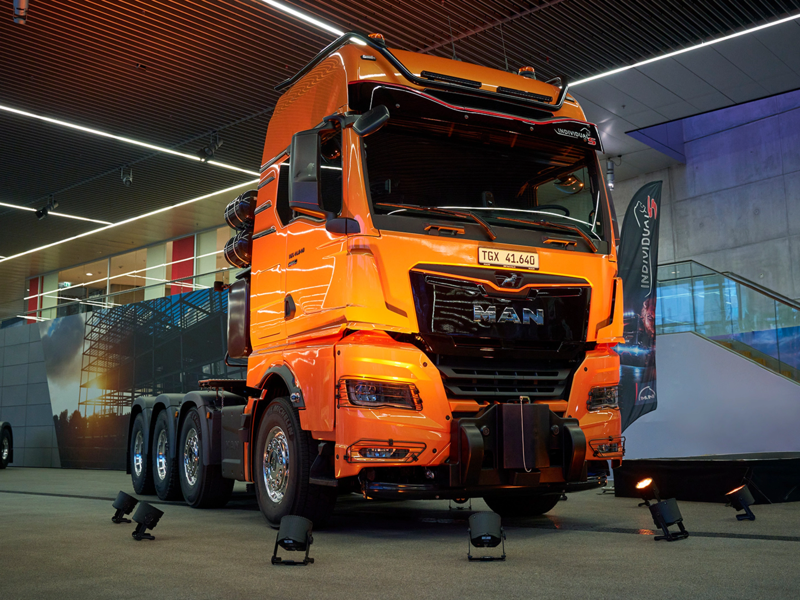 Orange MAN TGX 41.640 truck displayed at an indoor exhibition.