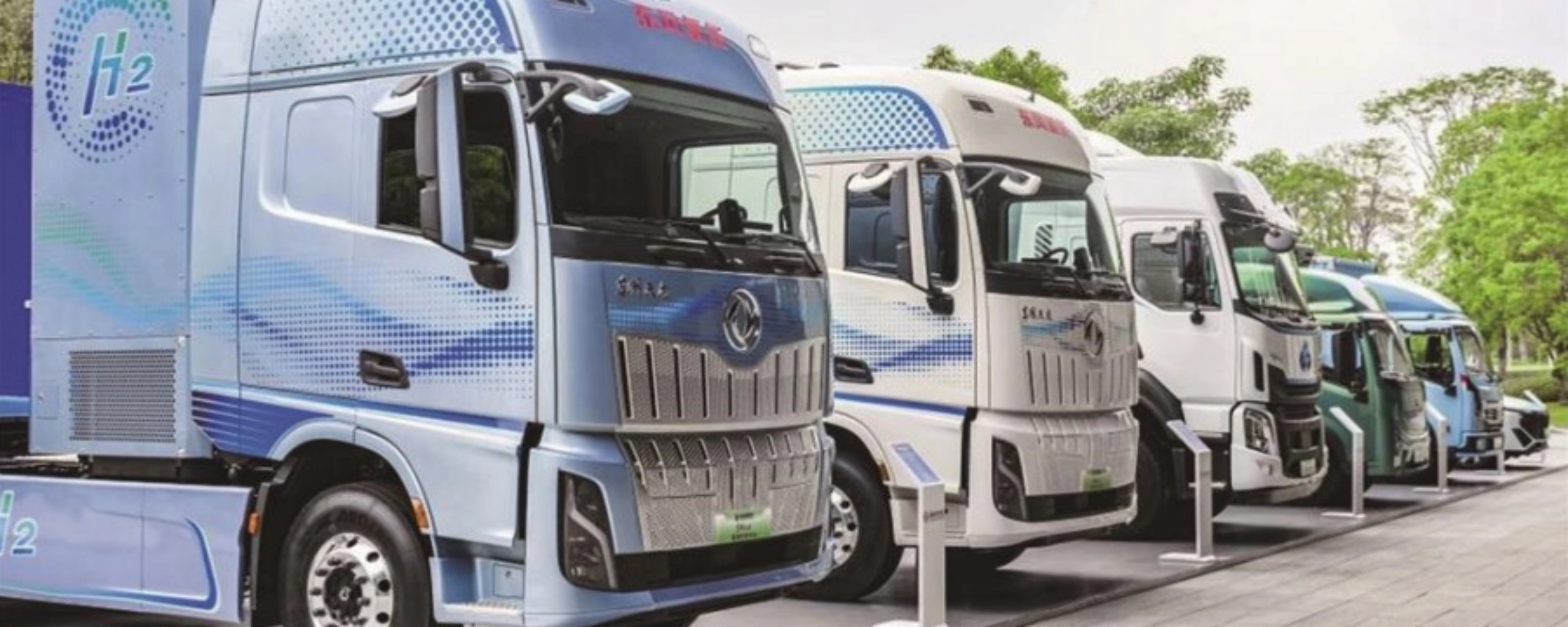 Reihe von Wasserstoff-Lkw mit H2-Beschriftung im Außenbereich.