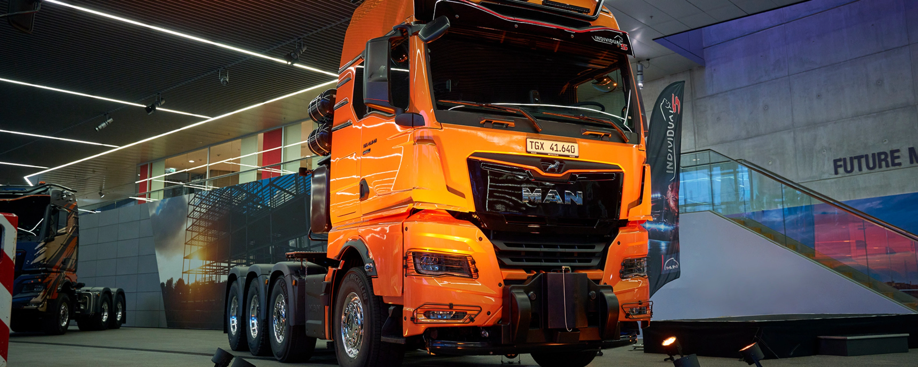 Orange MAN TGX 41.640 truck displayed at an indoor exhibition.