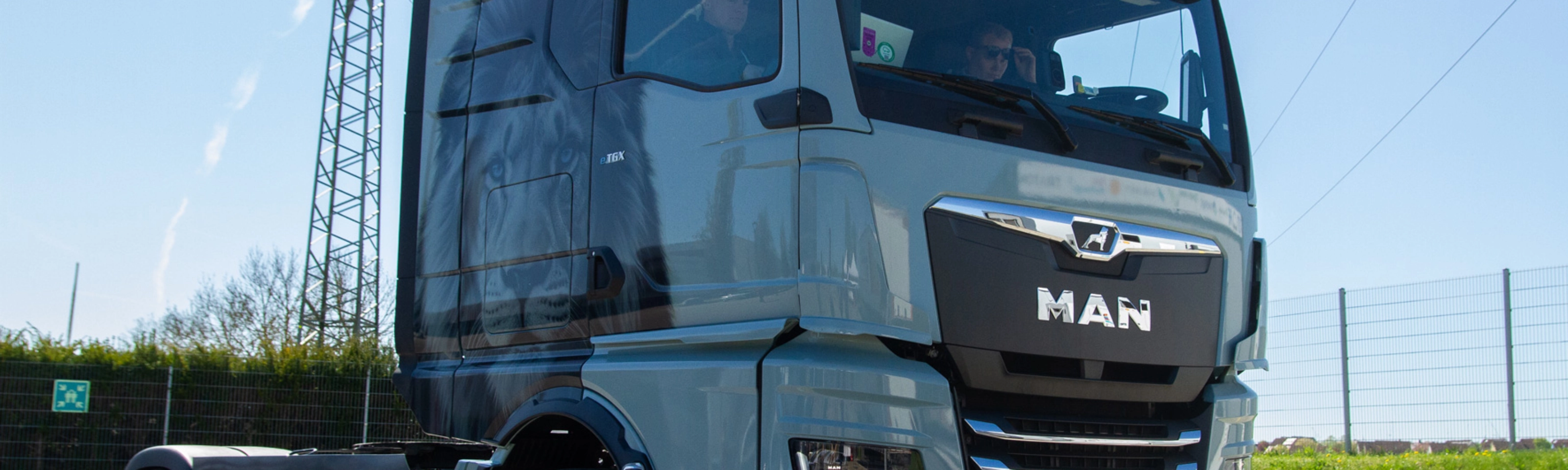 Light blue MAN truck in three-quarter front view on an open road.