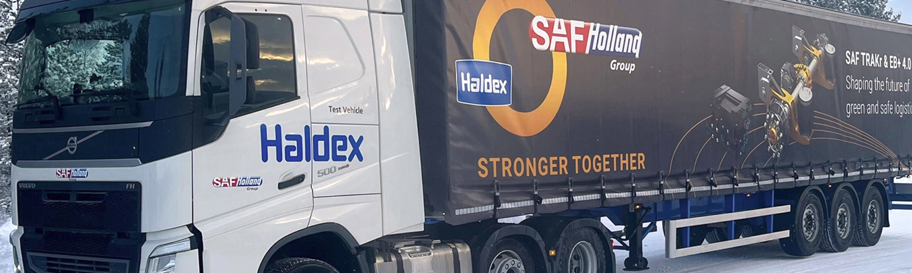 SAF-Holland truck with trailer driving on a snow-covered road.