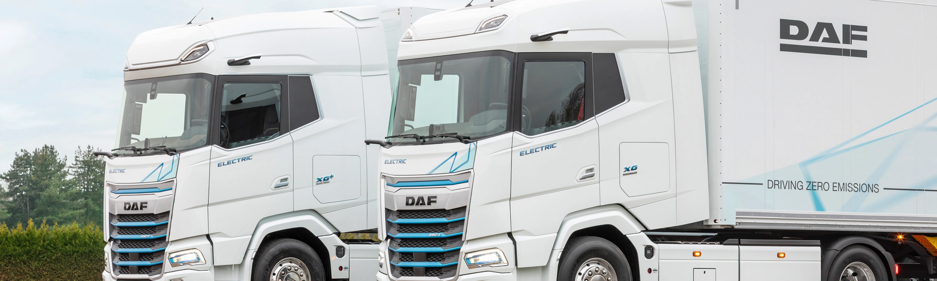 Two DAF electric trucks parked side by side outdoors.