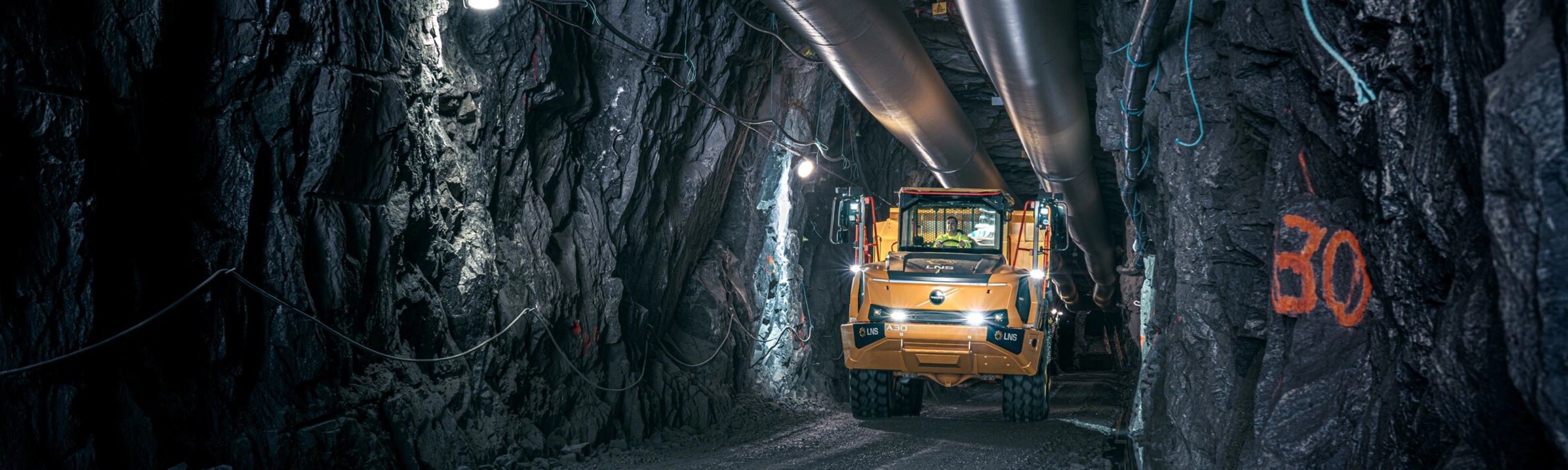 Orange Volvo truck driving through an underground mining tunnel.
