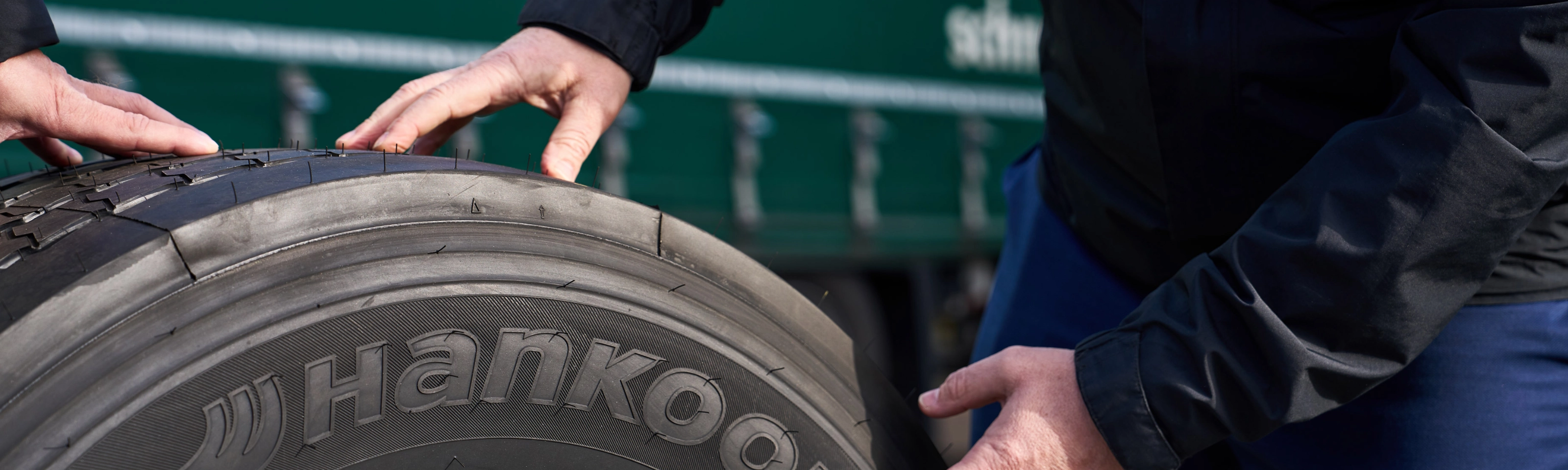 Hände prüfen einen Hankook-Lkw-Reifen auf einer Felge.