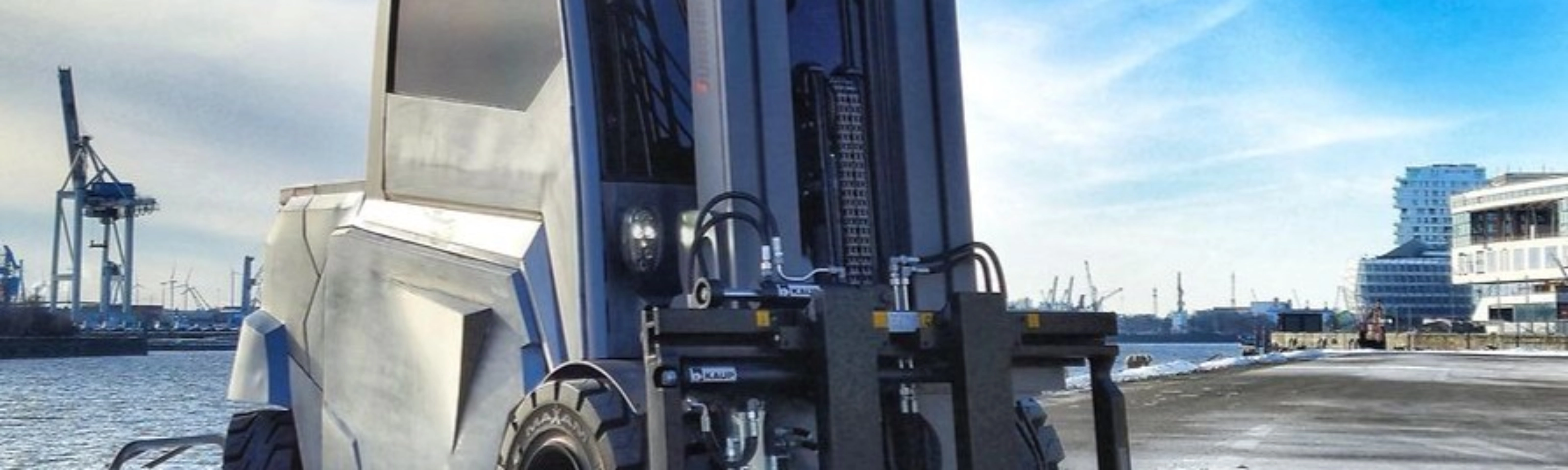Large industrial forklift parked at a harbor loading area.