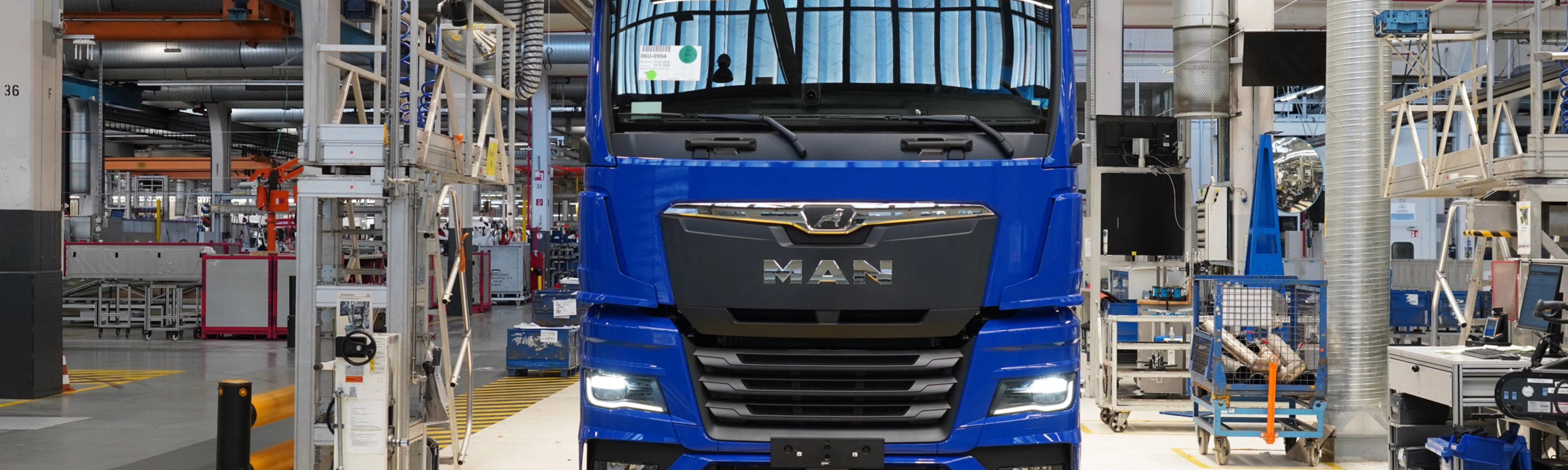 Blauer MAN-Lkw auf einer Produktionslinie in einer modernen Fertigungshalle.