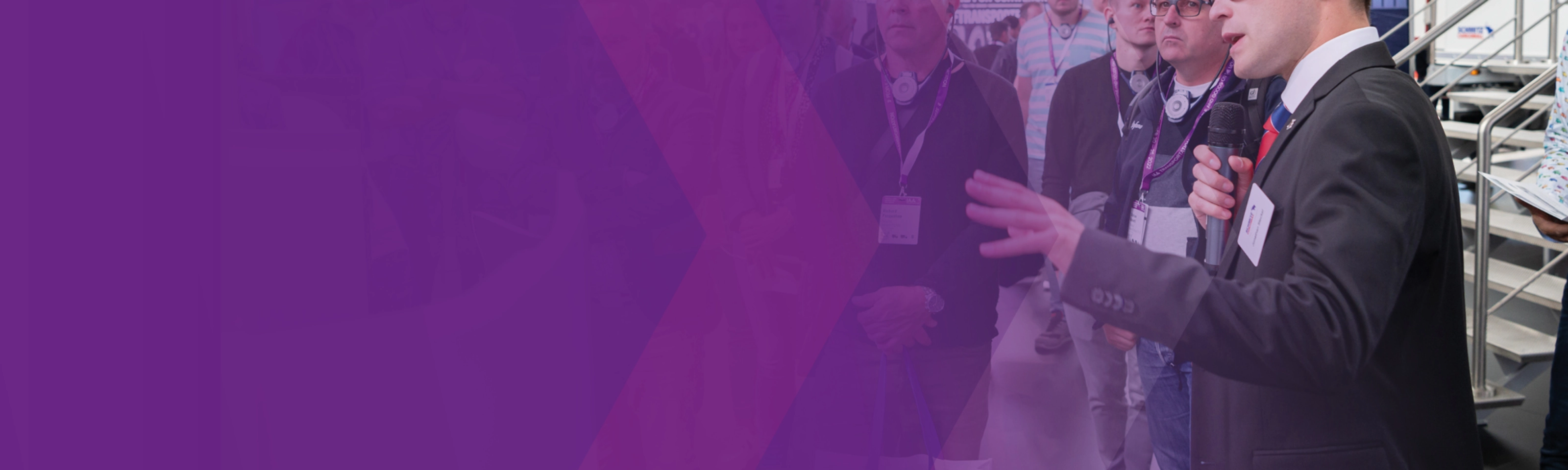 Ein Referent spricht während einer geführten Tour zu einer Gruppe auf einer Messe.