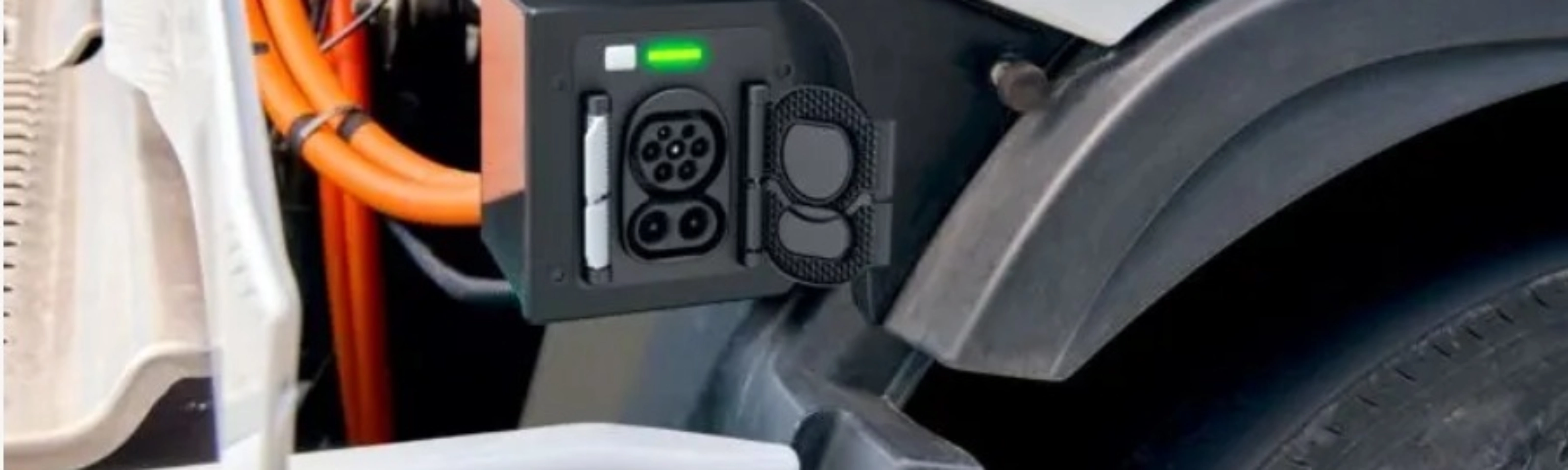 Charging port of an electric truck with visible high-voltage cables and a green status light.