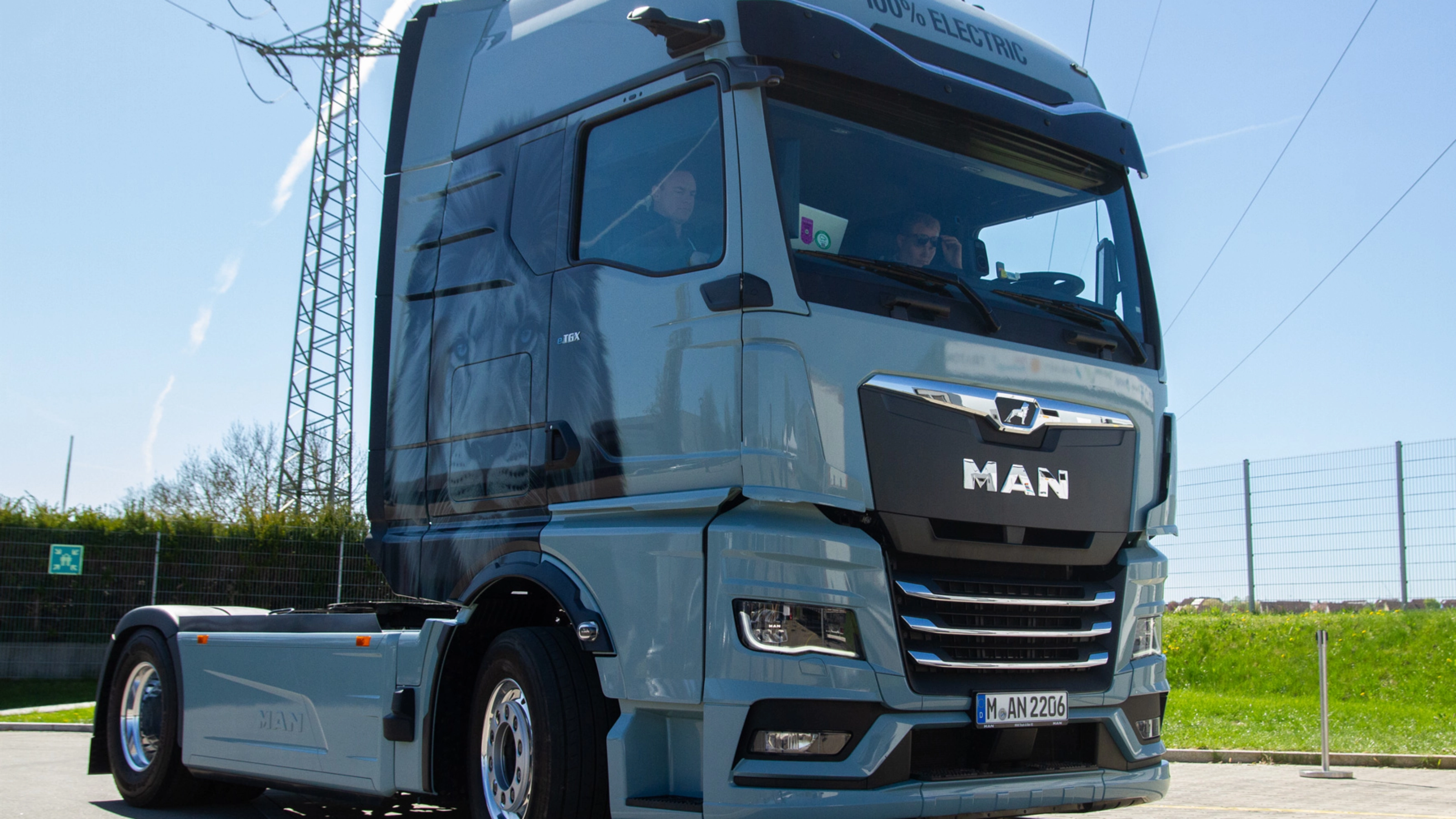 Light blue MAN truck in three-quarter front view on an open road.