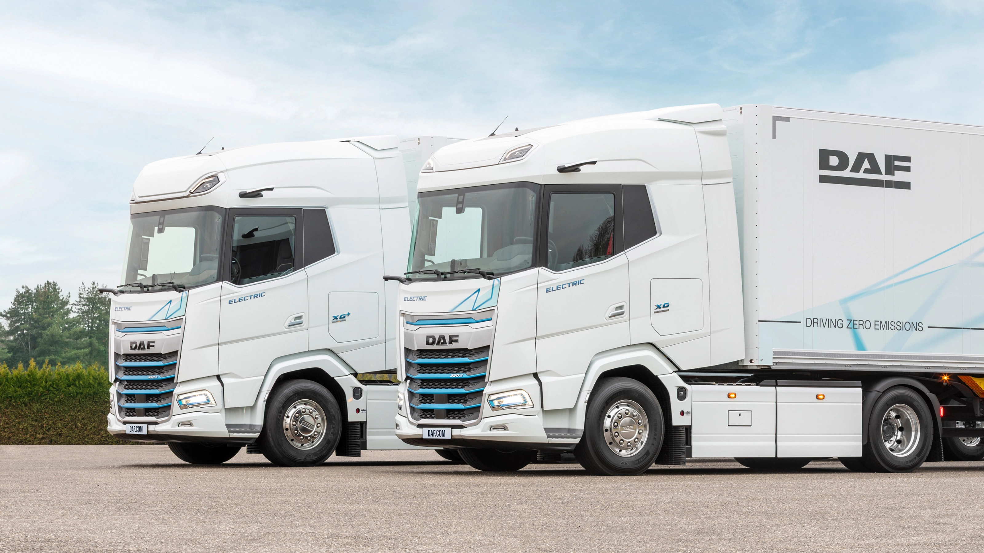Two DAF electric trucks parked side by side outdoors.