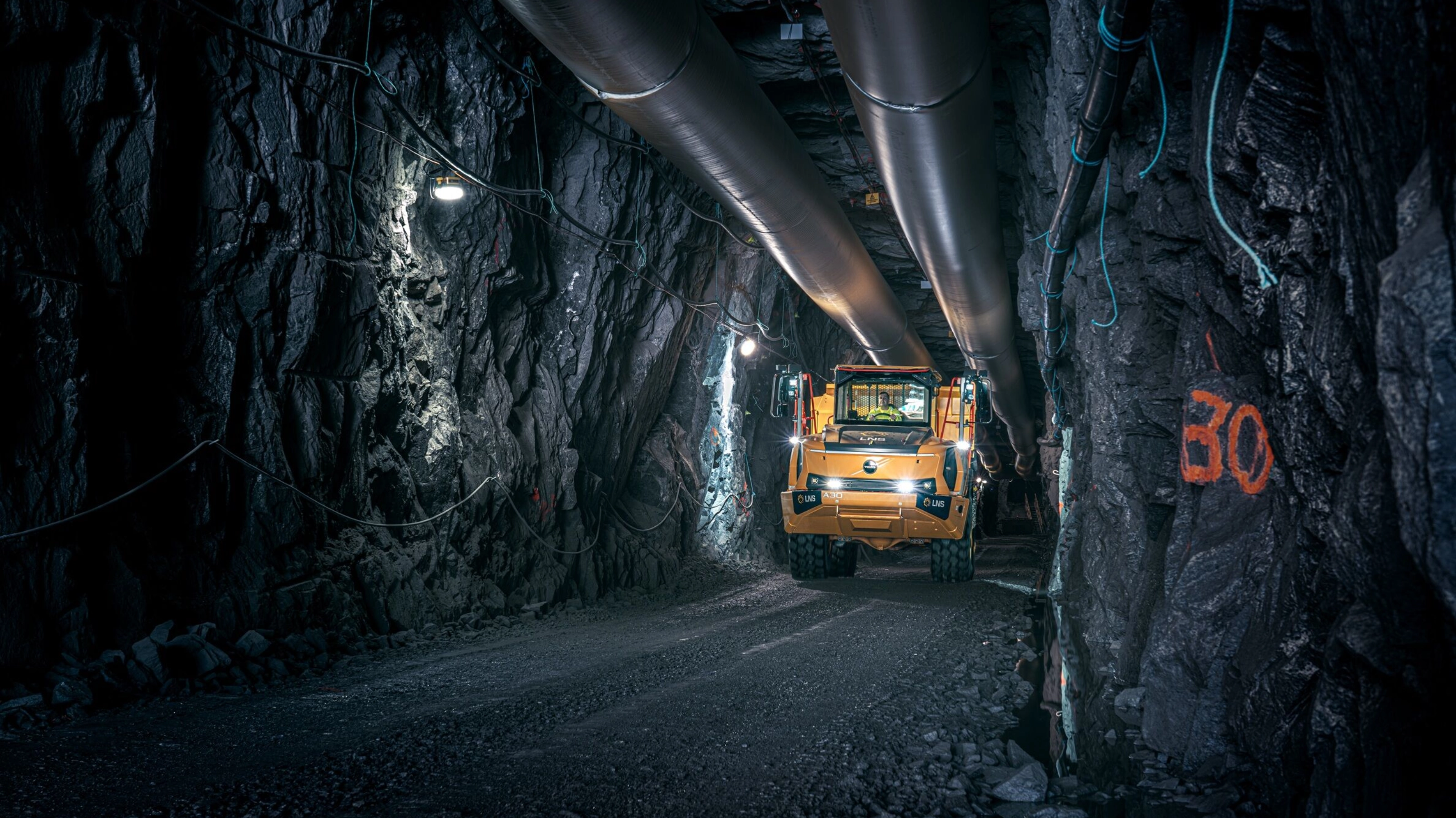 Orange Volvo truck driving through an underground mining tunnel.