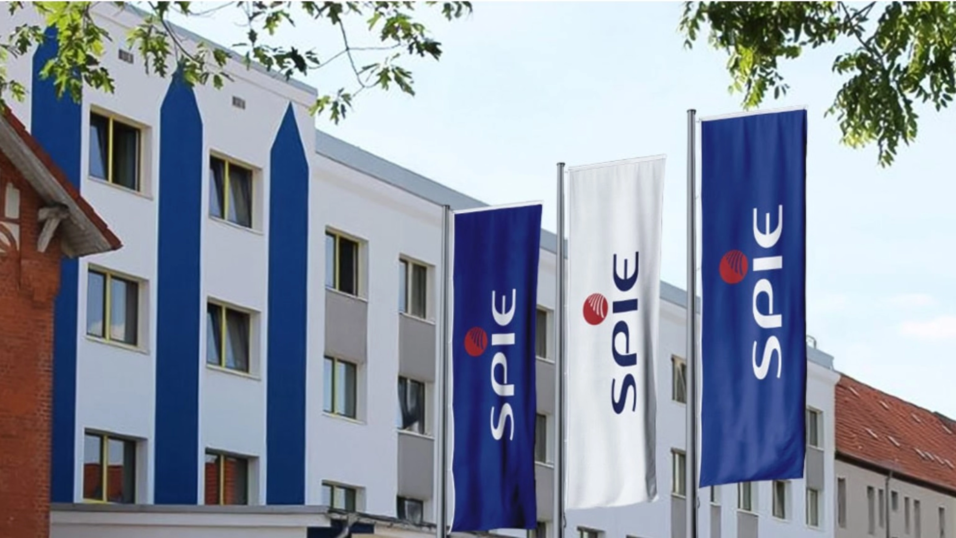 SPIE-Gebäude mit mehreren blauen SPIE-Flaggen an der Fassade.
