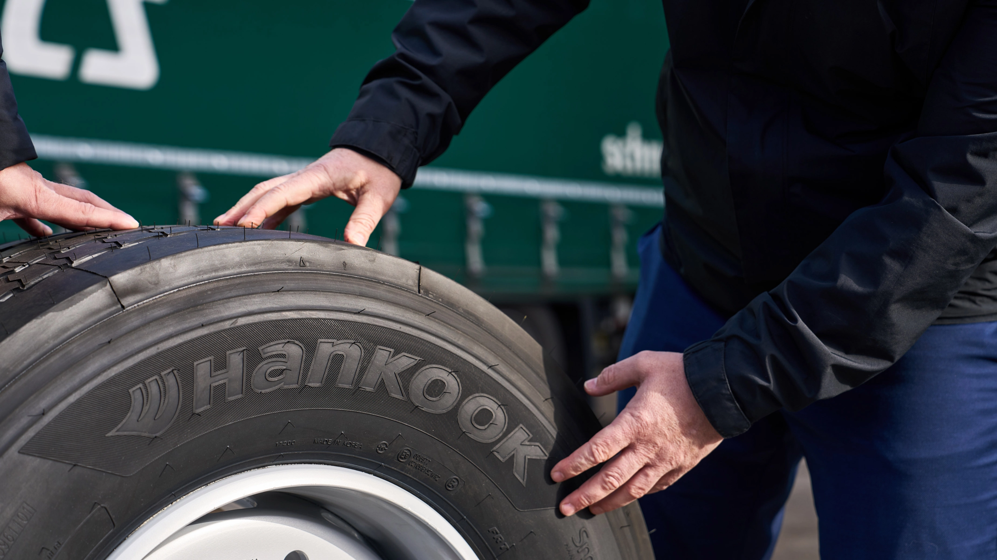 Hände prüfen einen Hankook-Lkw-Reifen auf einer Felge.