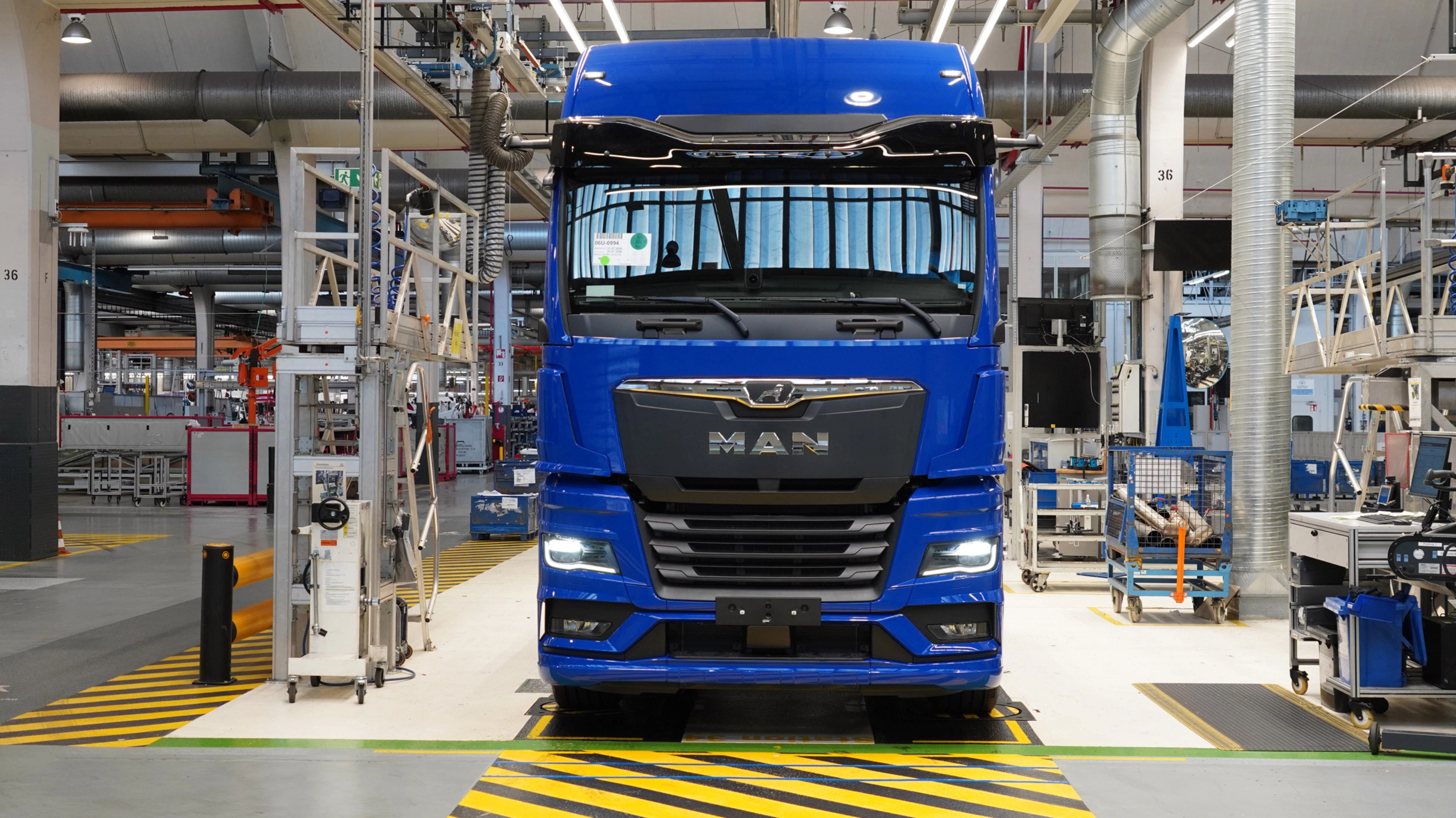 Blauer MAN-Lkw auf einer Produktionslinie in einer modernen Fertigungshalle.
