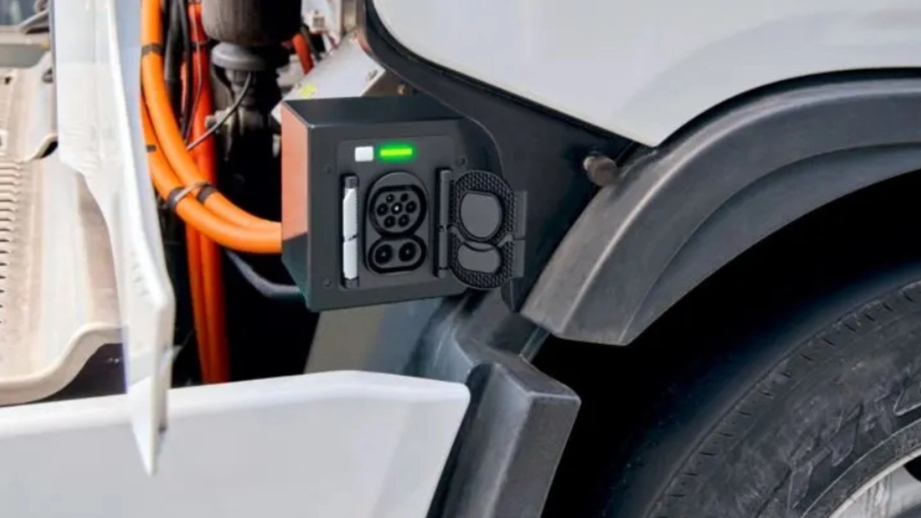 Charging port of an electric truck with visible high-voltage cables and a green status light.