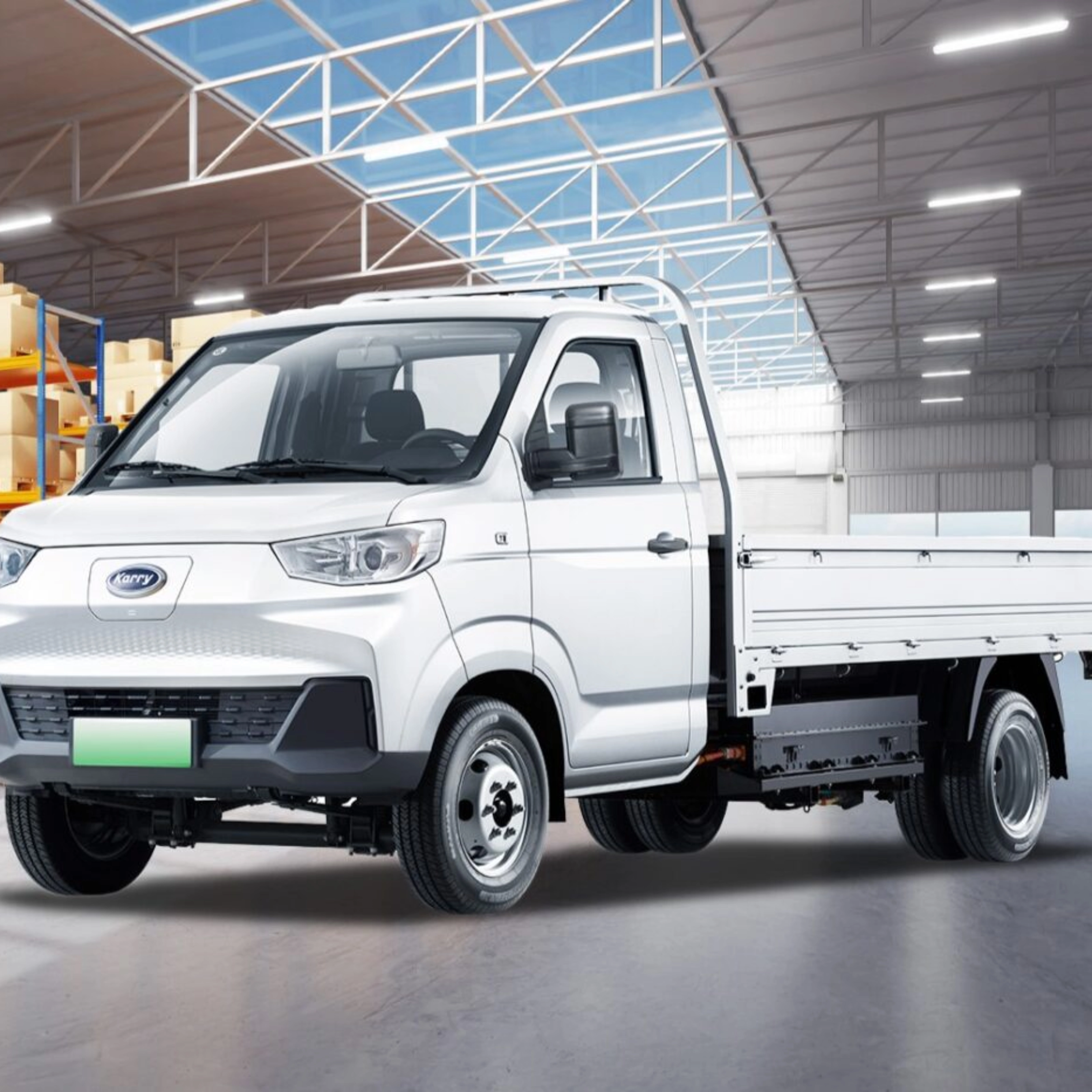A white Karry electric flatbed truck is parked inside a warehouse near stacked boxes.