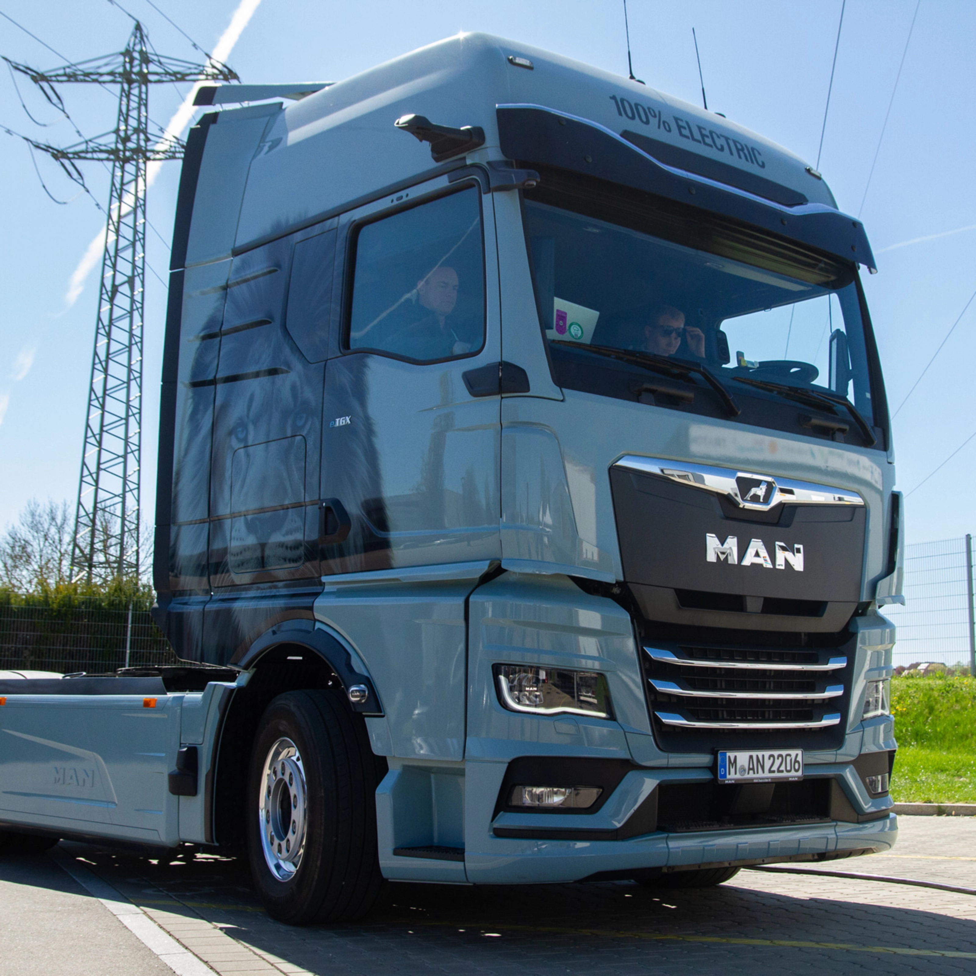 Light blue MAN truck in three-quarter front view on an open road.