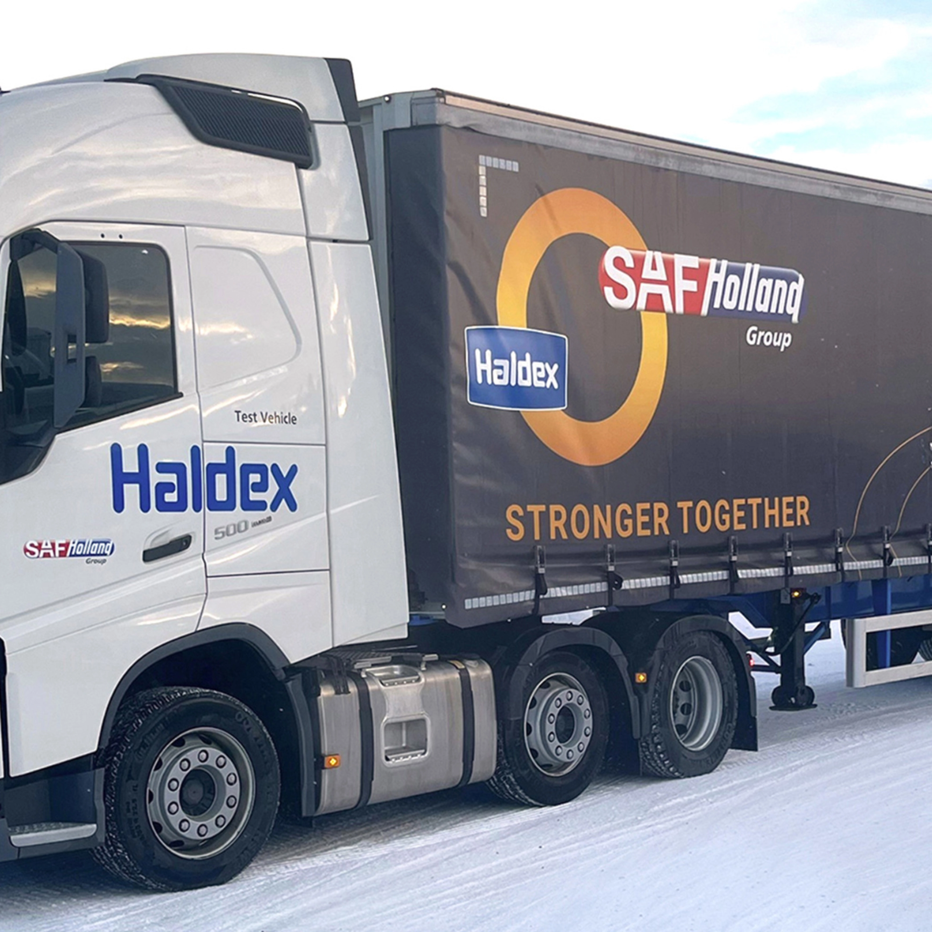 SAF-Holland truck with trailer driving on a snow-covered road.