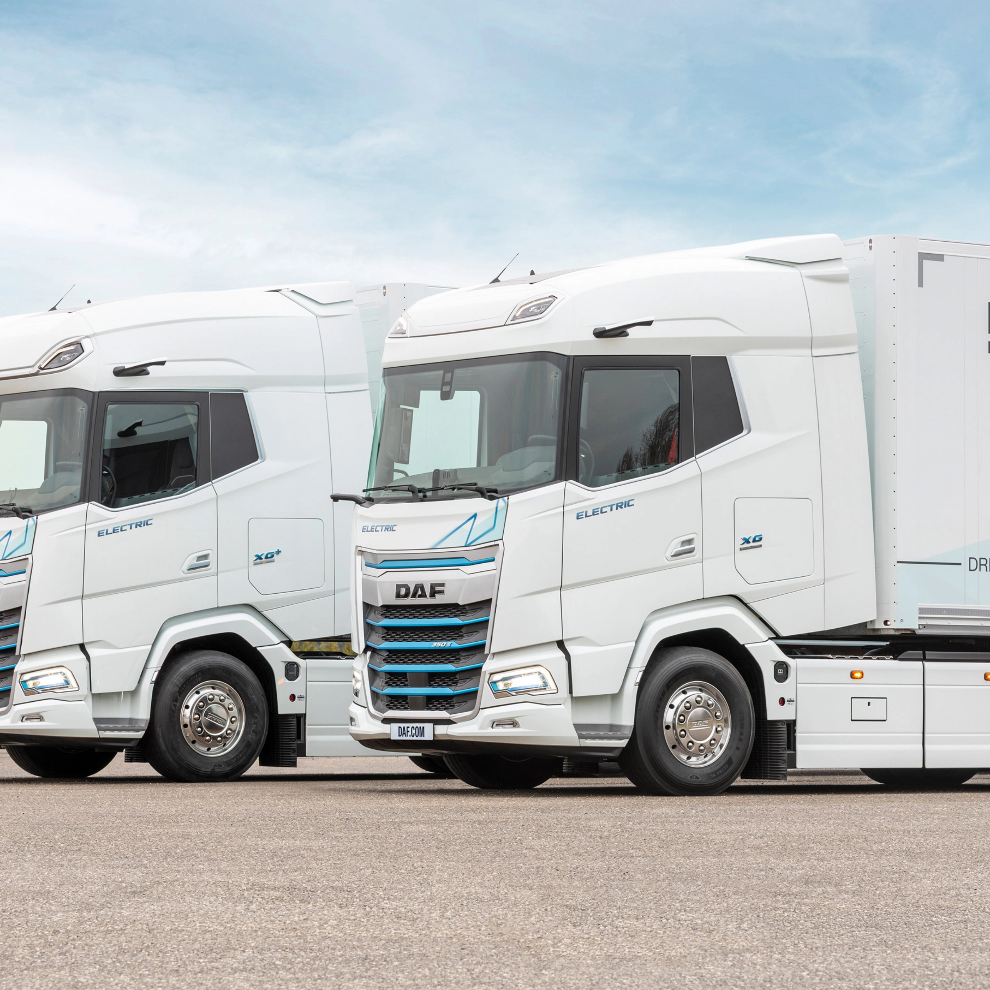 Two DAF electric trucks parked side by side outdoors.